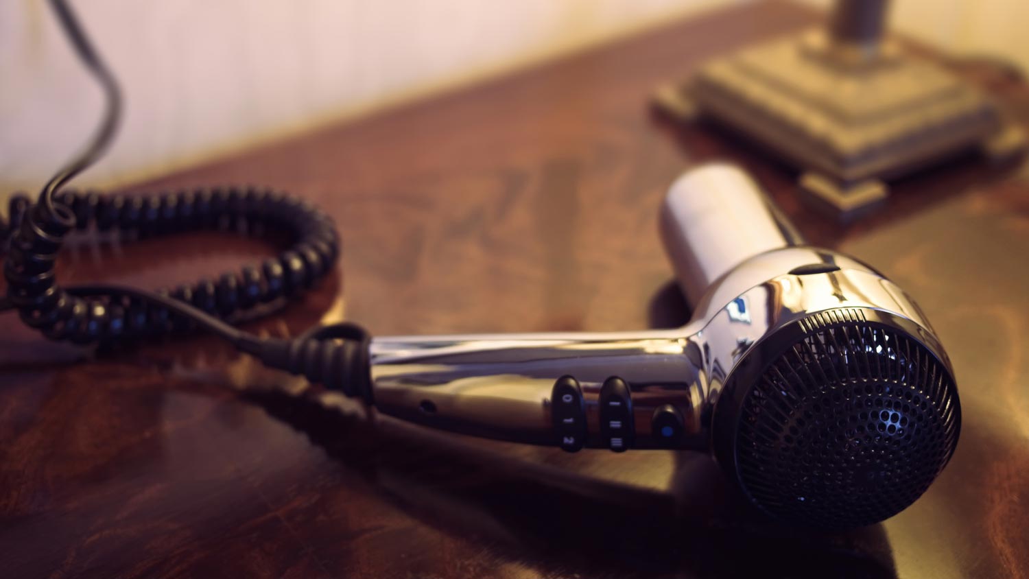 A hairdryer on a wooden night stand