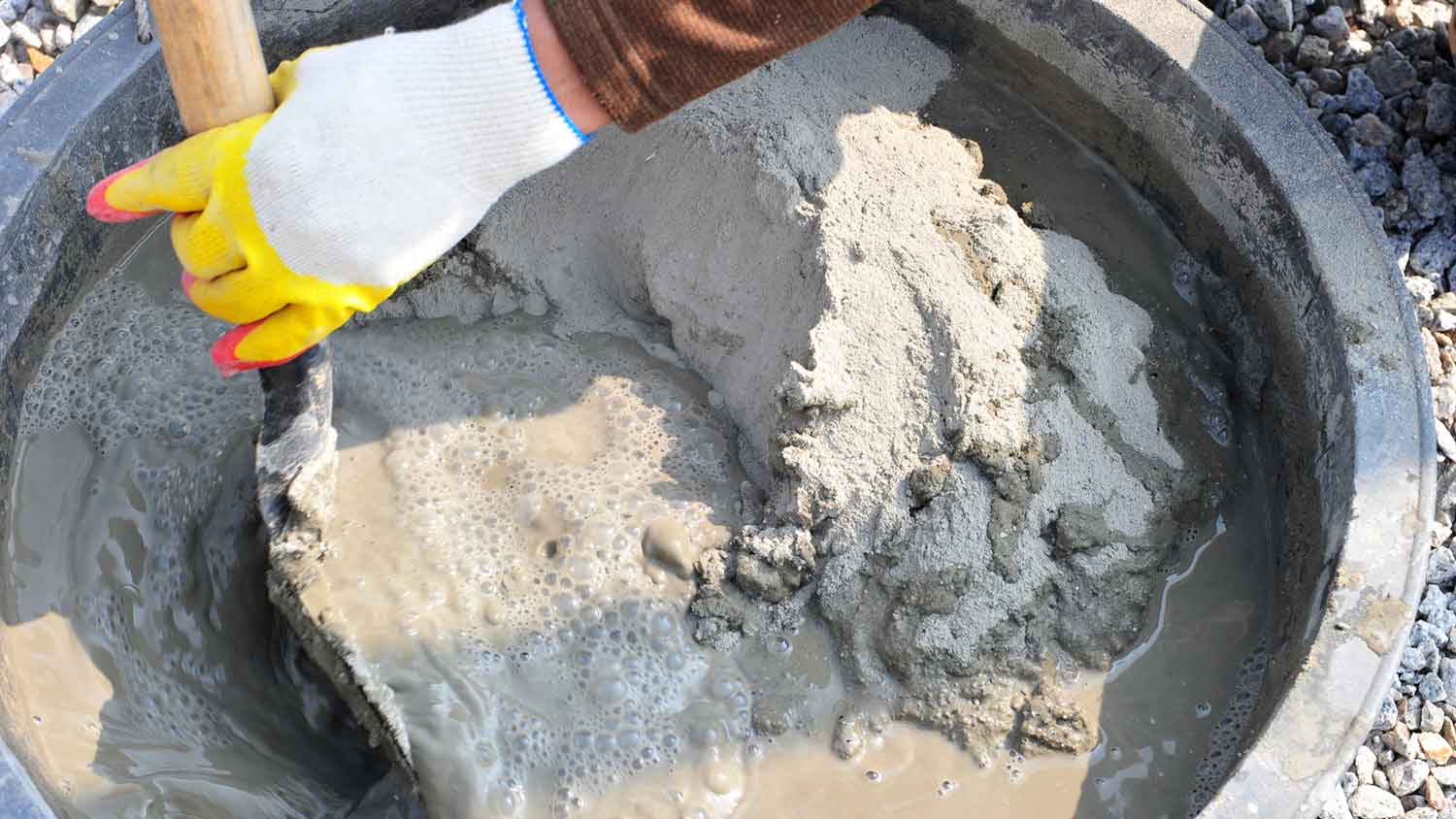 Worker using shovel to mix cement 