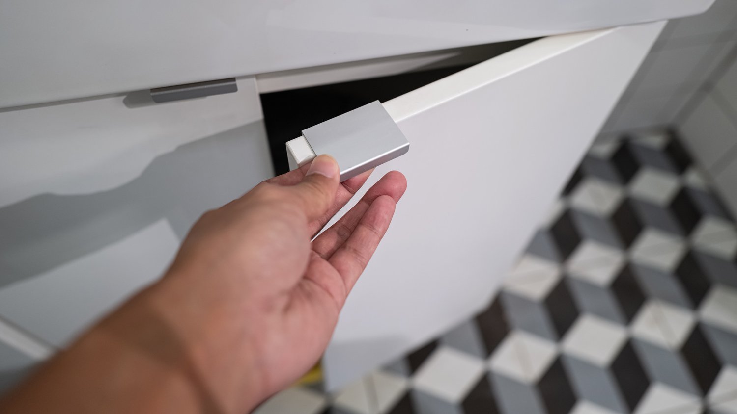 Human hand touches the door handle of the cabinet 