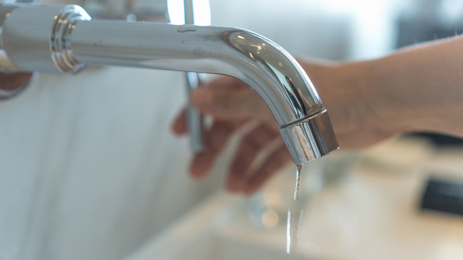 woman holding handle of dripping faucet