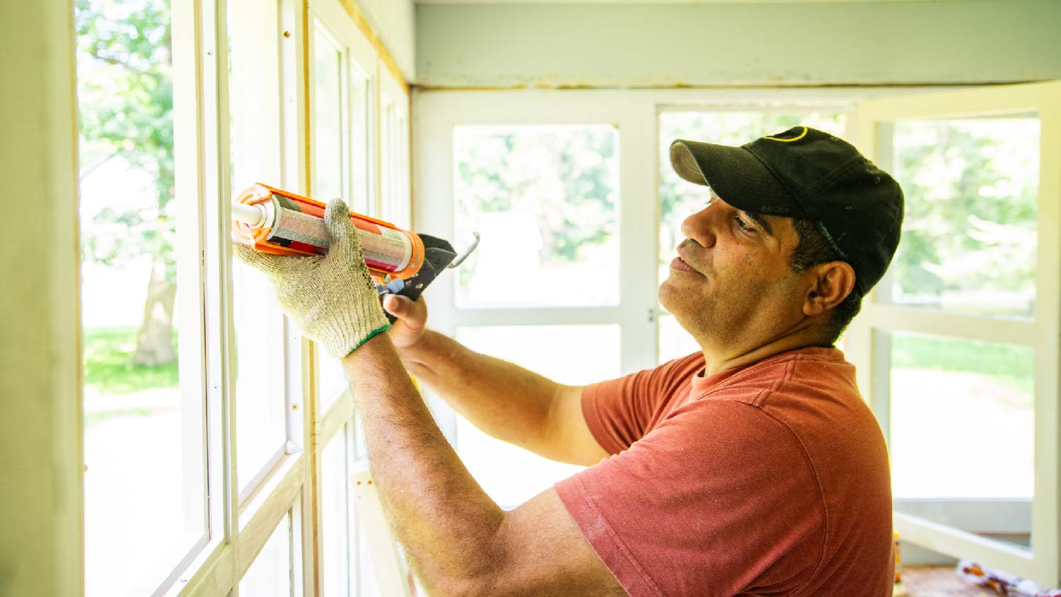 A handyman caulking a window