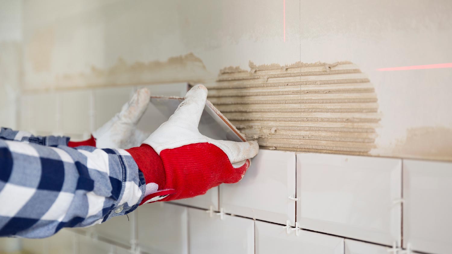 A handyman installing tiles for backsplash