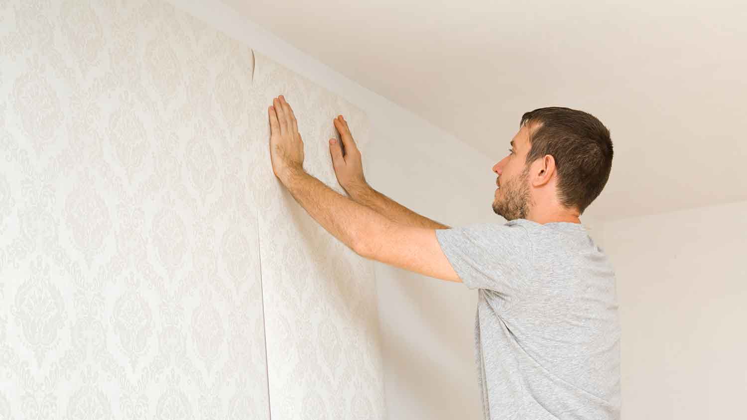 Handyperson hanging new wallpaper on the wall