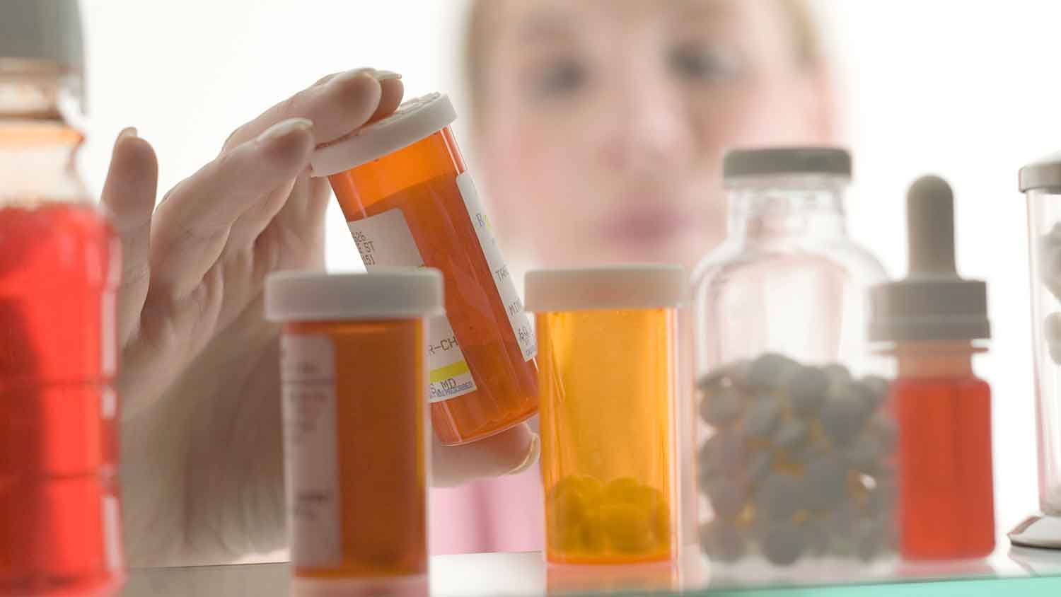 Woman taking medicine bottle from the cabinet 