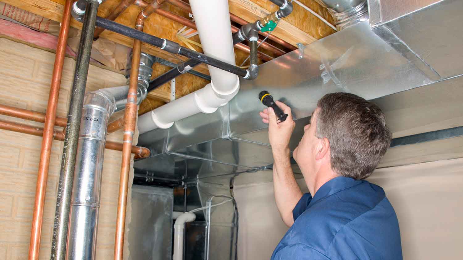 Inspector checking pipes in the basement