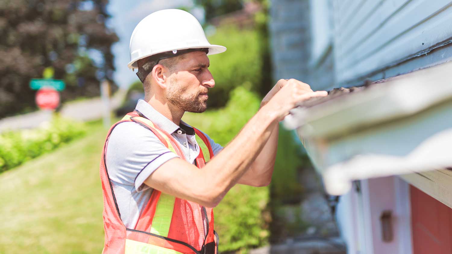 Home inspector on a ladder checking the roof of a house