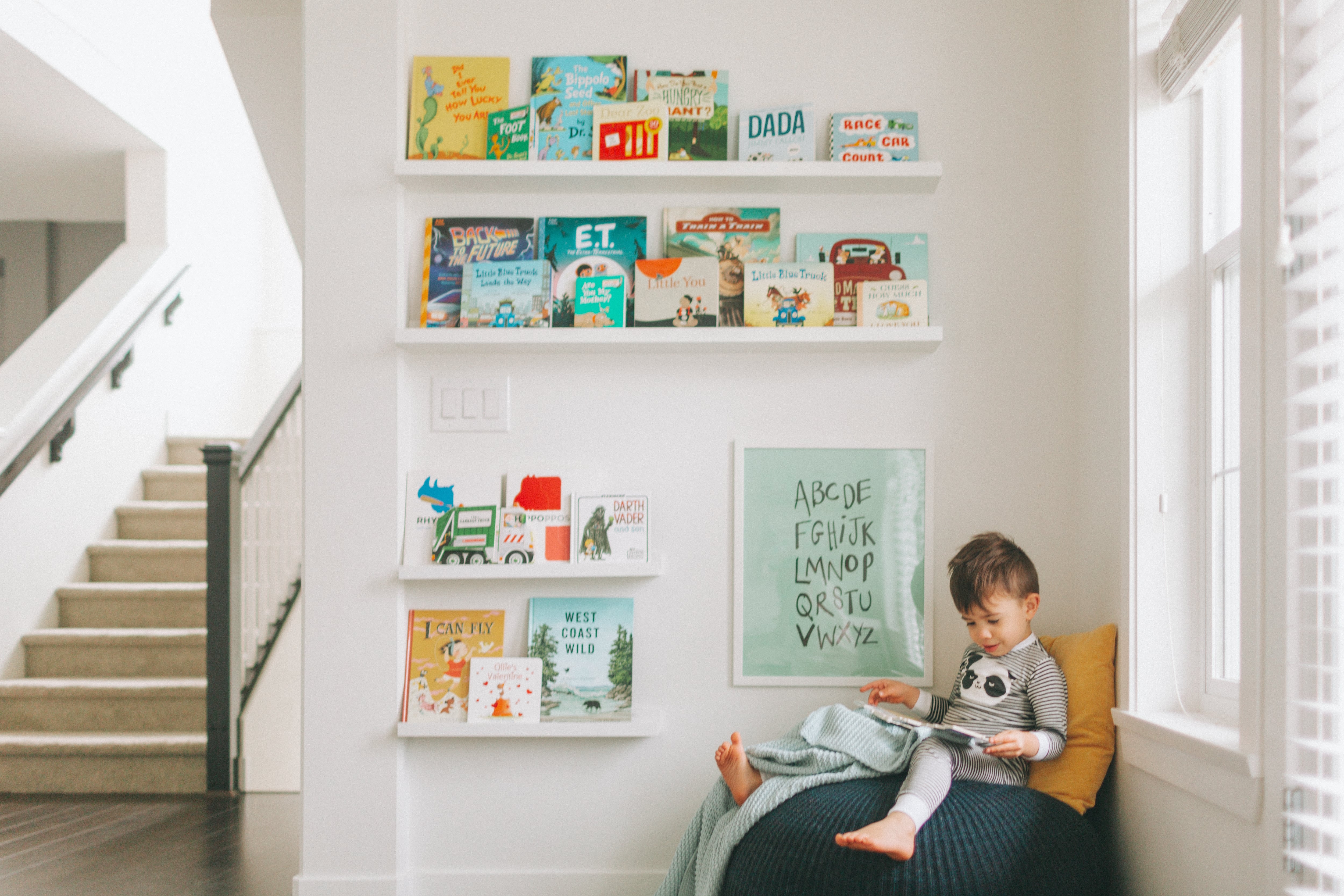 A little boy reading in a corner of his playroom