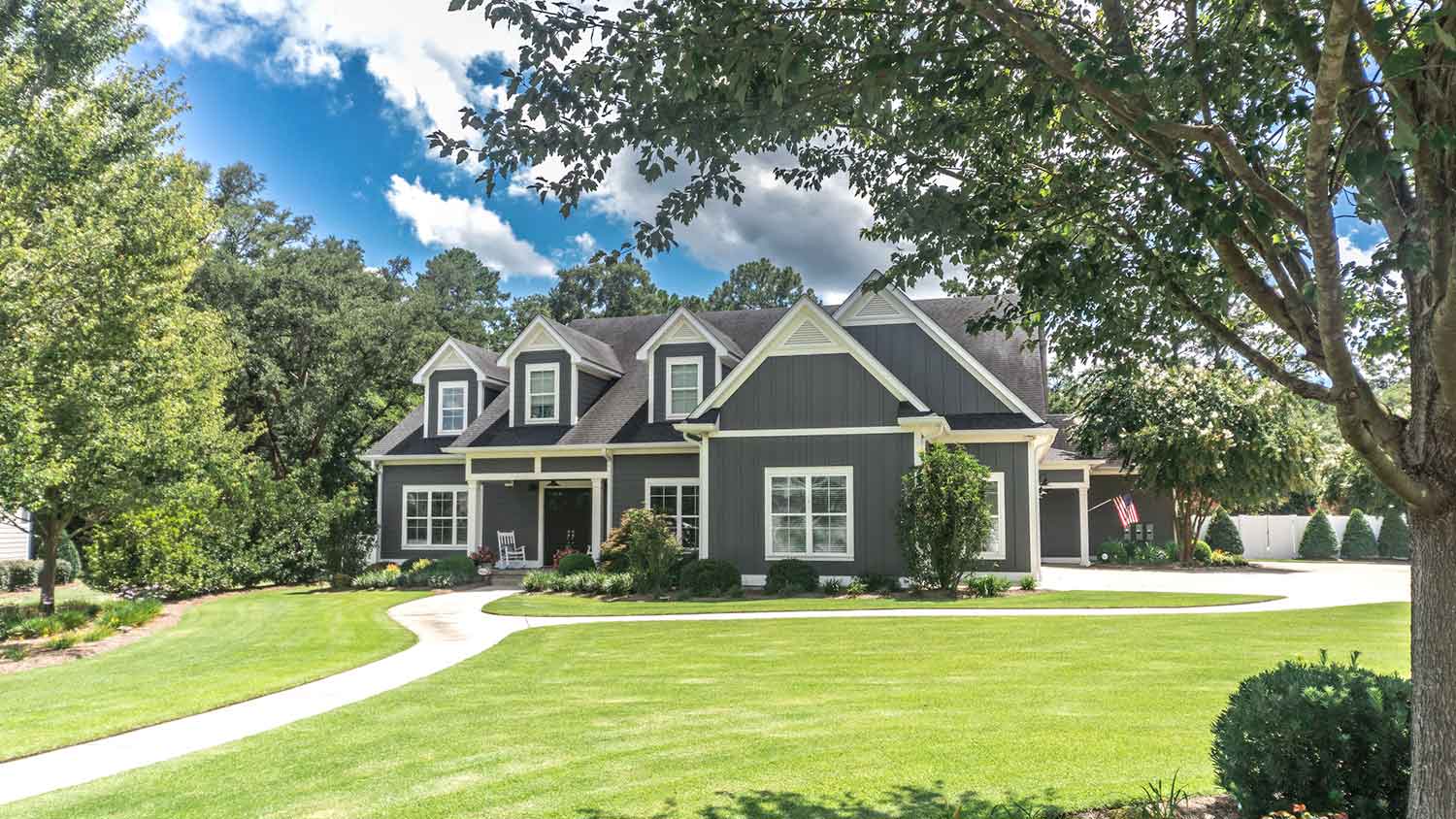 Gray sided house with large front yard and a pathway