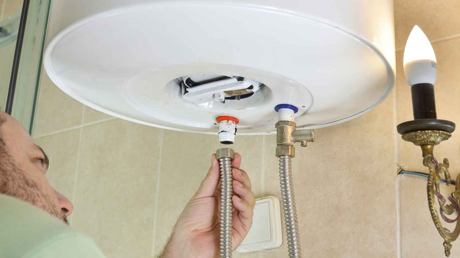 Man installing hot and cold-water pipes on a water heater