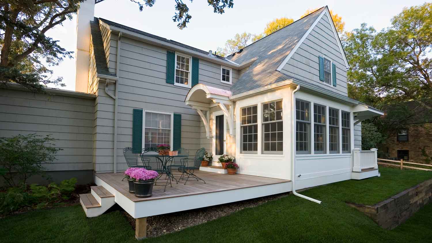 An evergreen fog painted house with a wooden deck