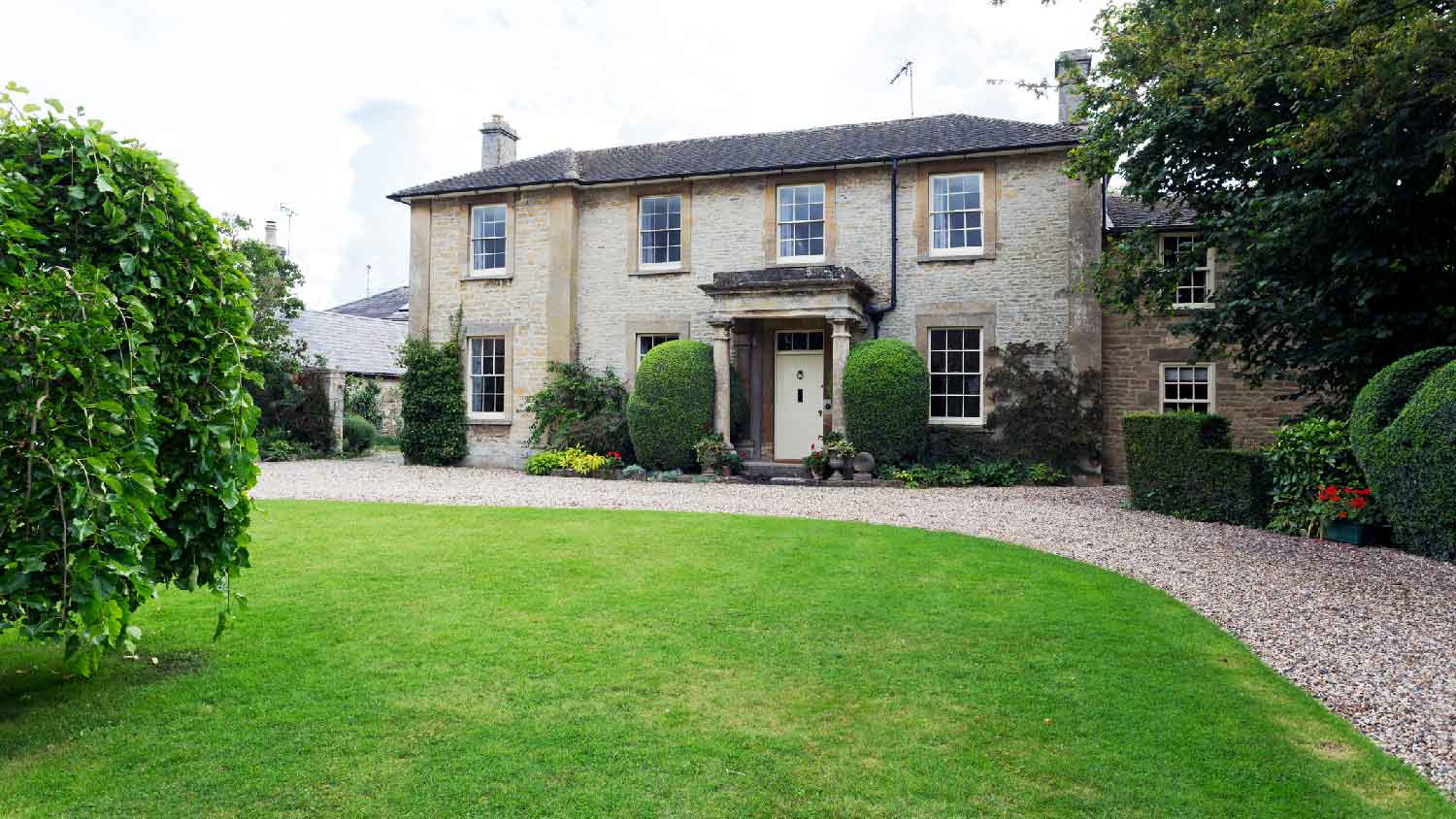 A two-story house with decomposed granite driveway