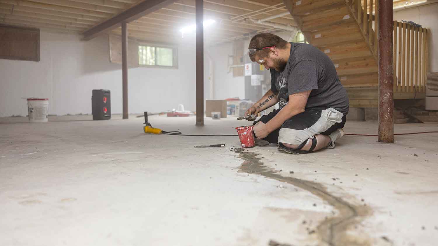 Worker sealing basement floor cracks