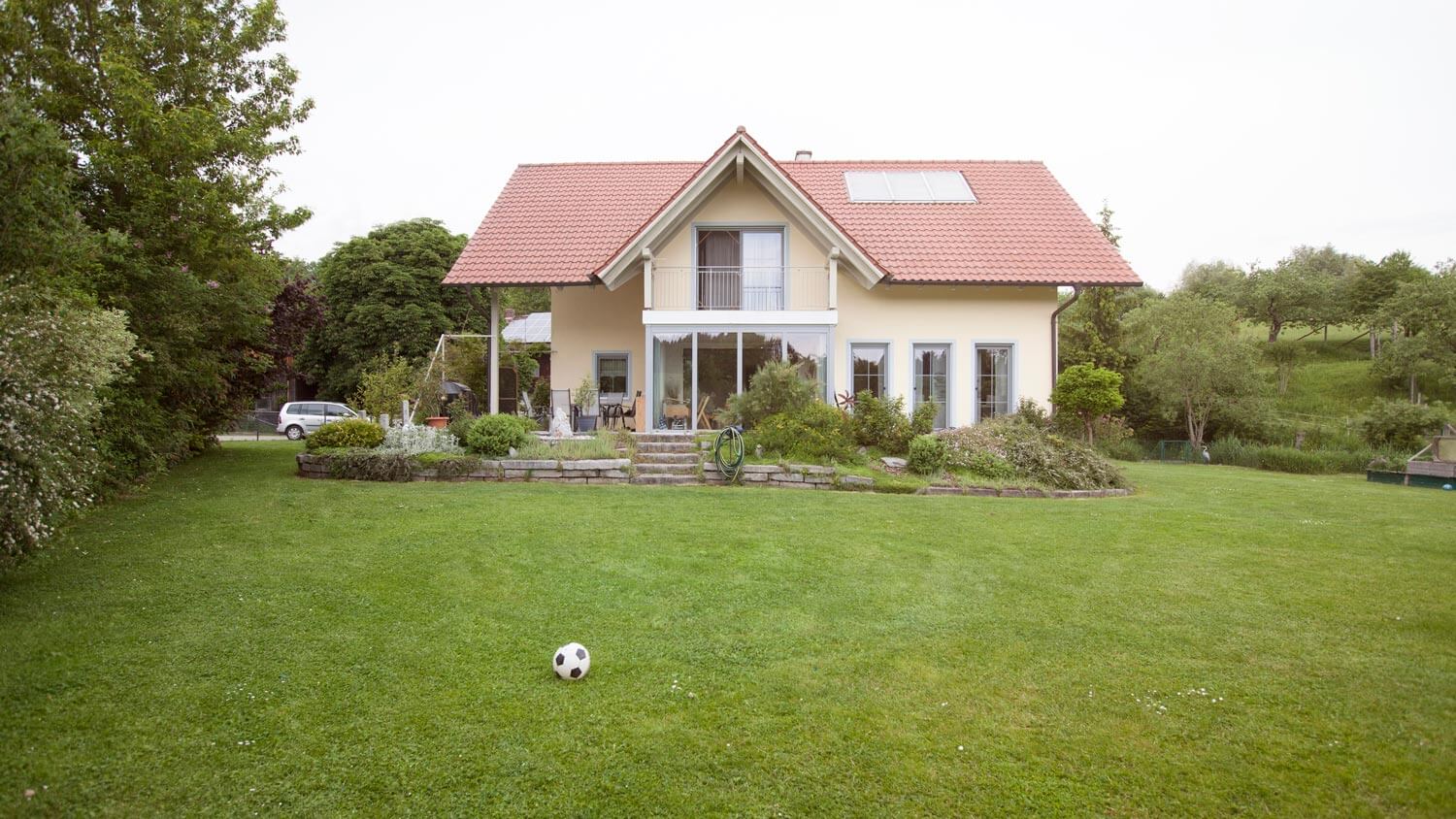 A house’s front yard with freshly cut lawn and a soccer ball