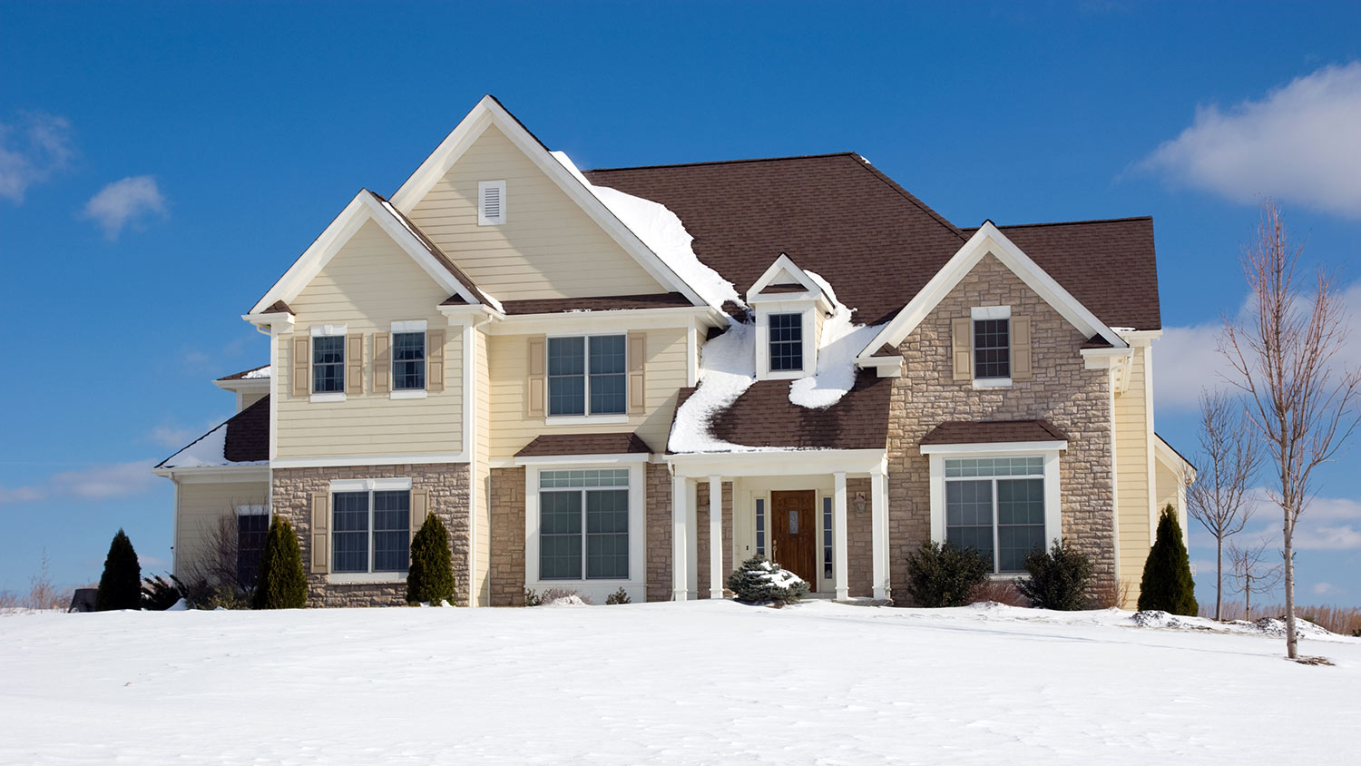 Contemporary home with brown shingle roof covered in snow