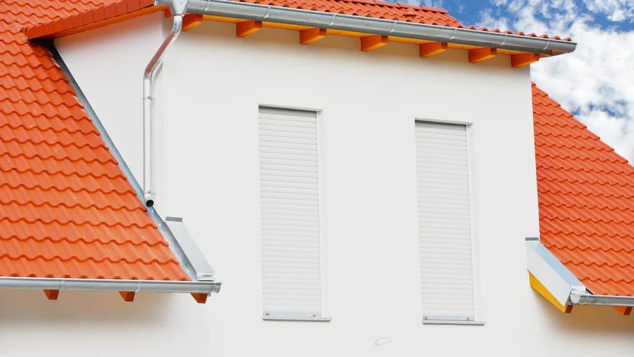 A house with two windows having rolling exterior shutters