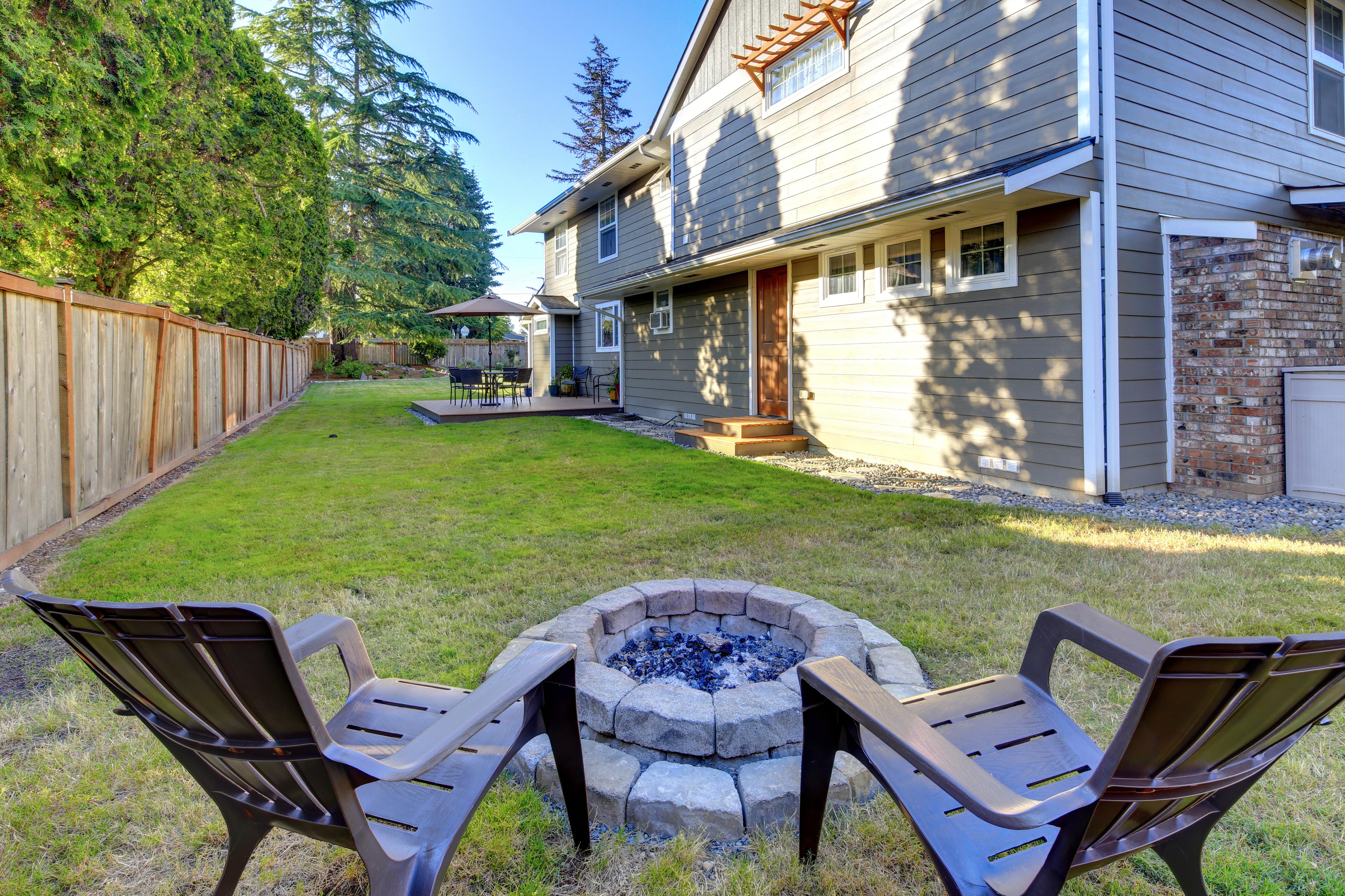 Ring fire pit and two adirondack chairs in a spacious backyard