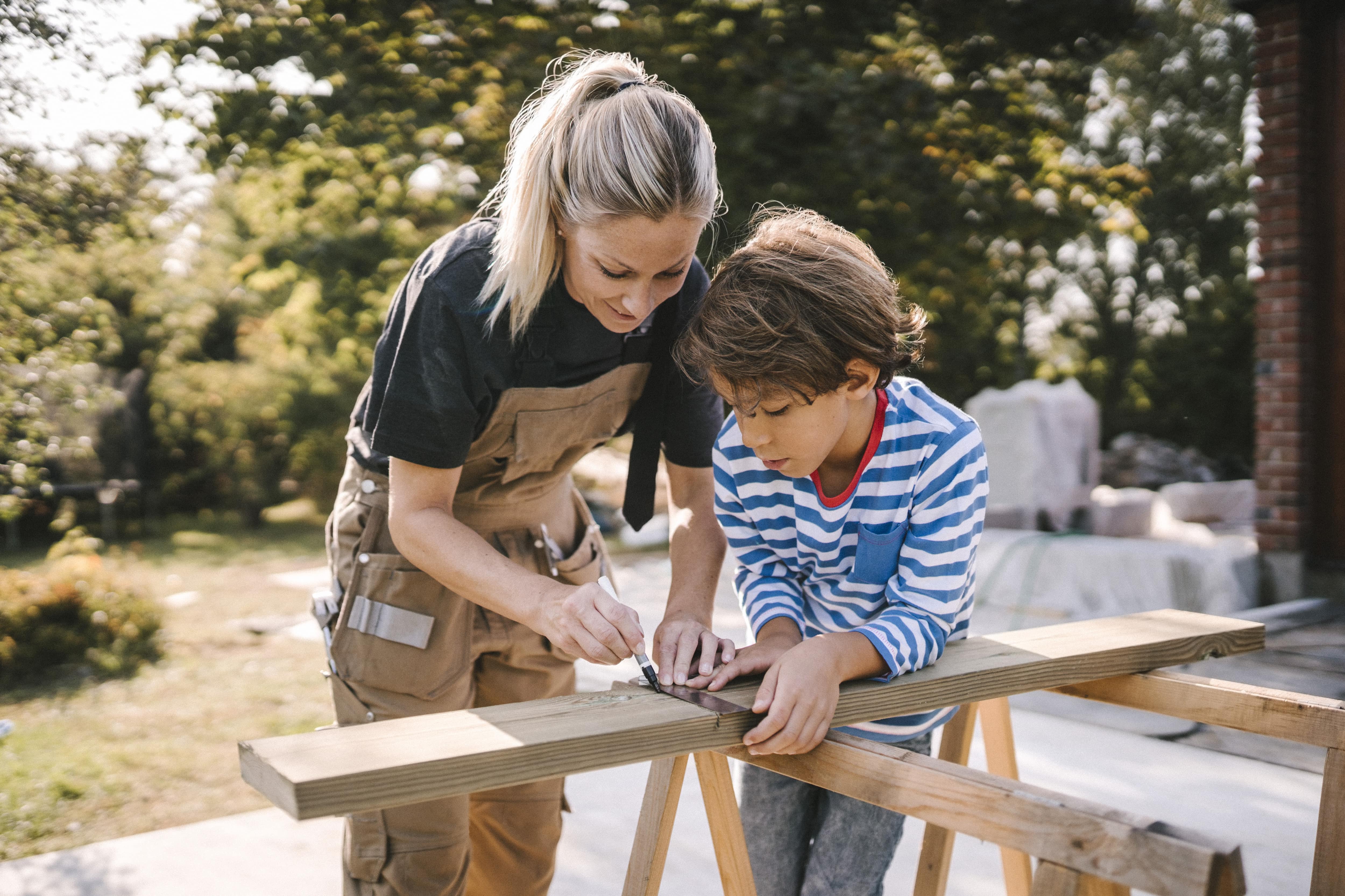 A mother and son measure a plank of wood