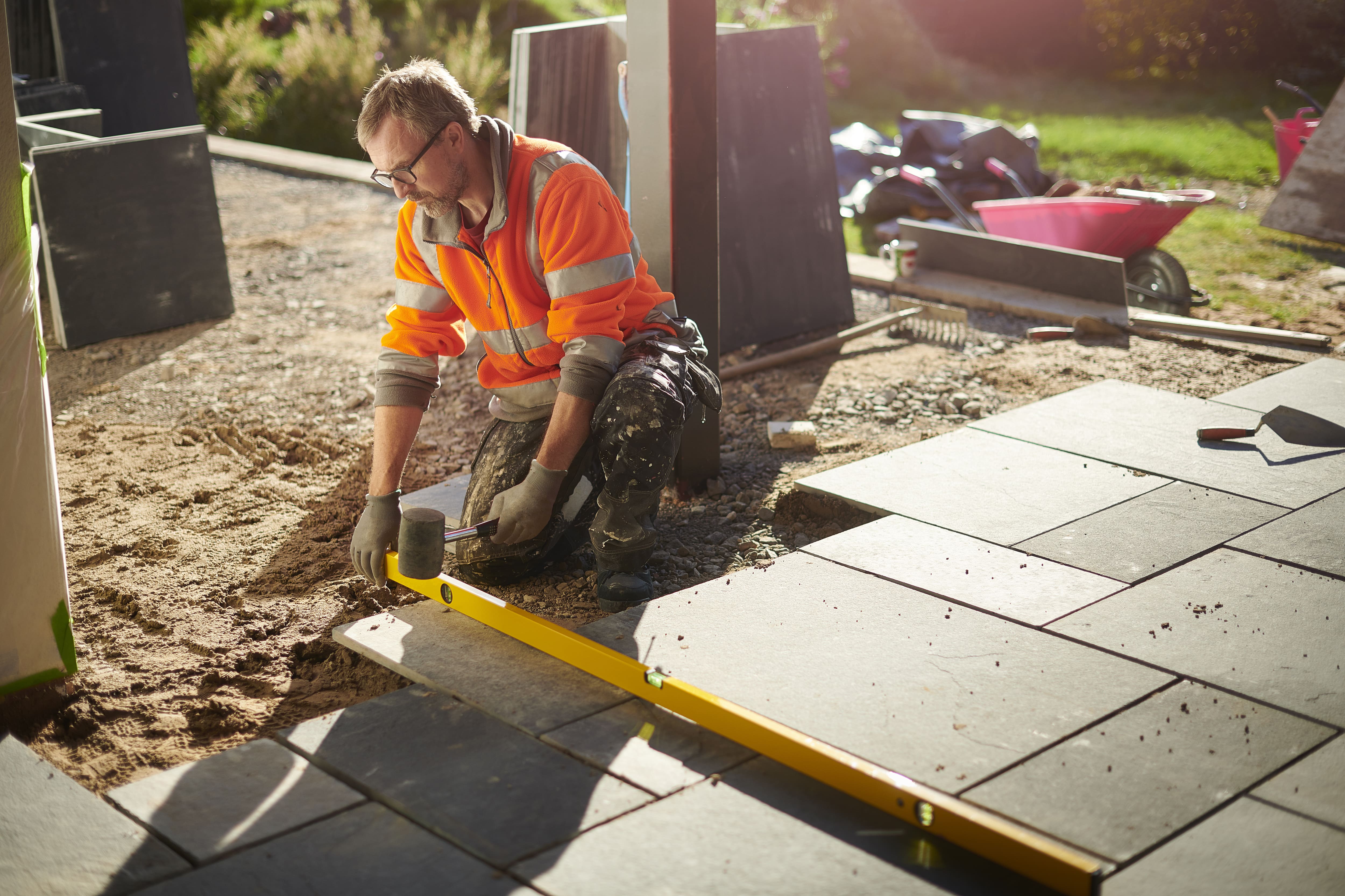 A construction worker using a mallet to install a bluestone paver patio