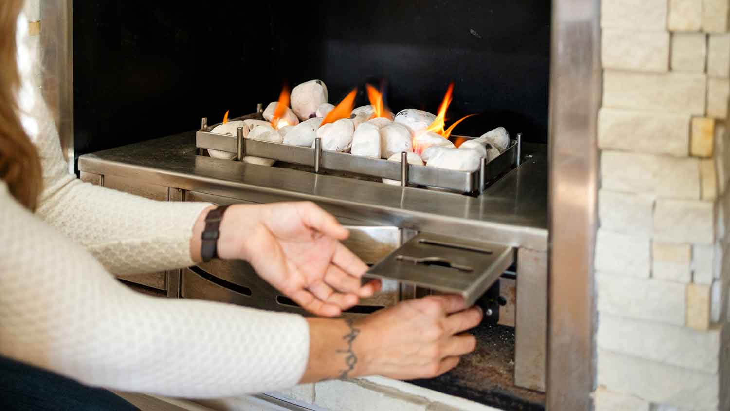 Woman using switch to ignite gas fireplace 