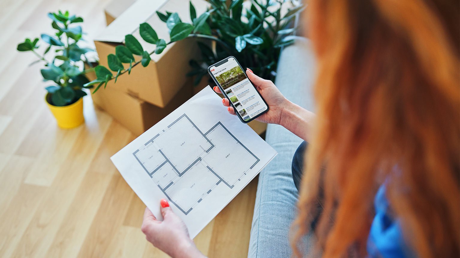 Close up of new apartment plans and smartphone being held by young woman