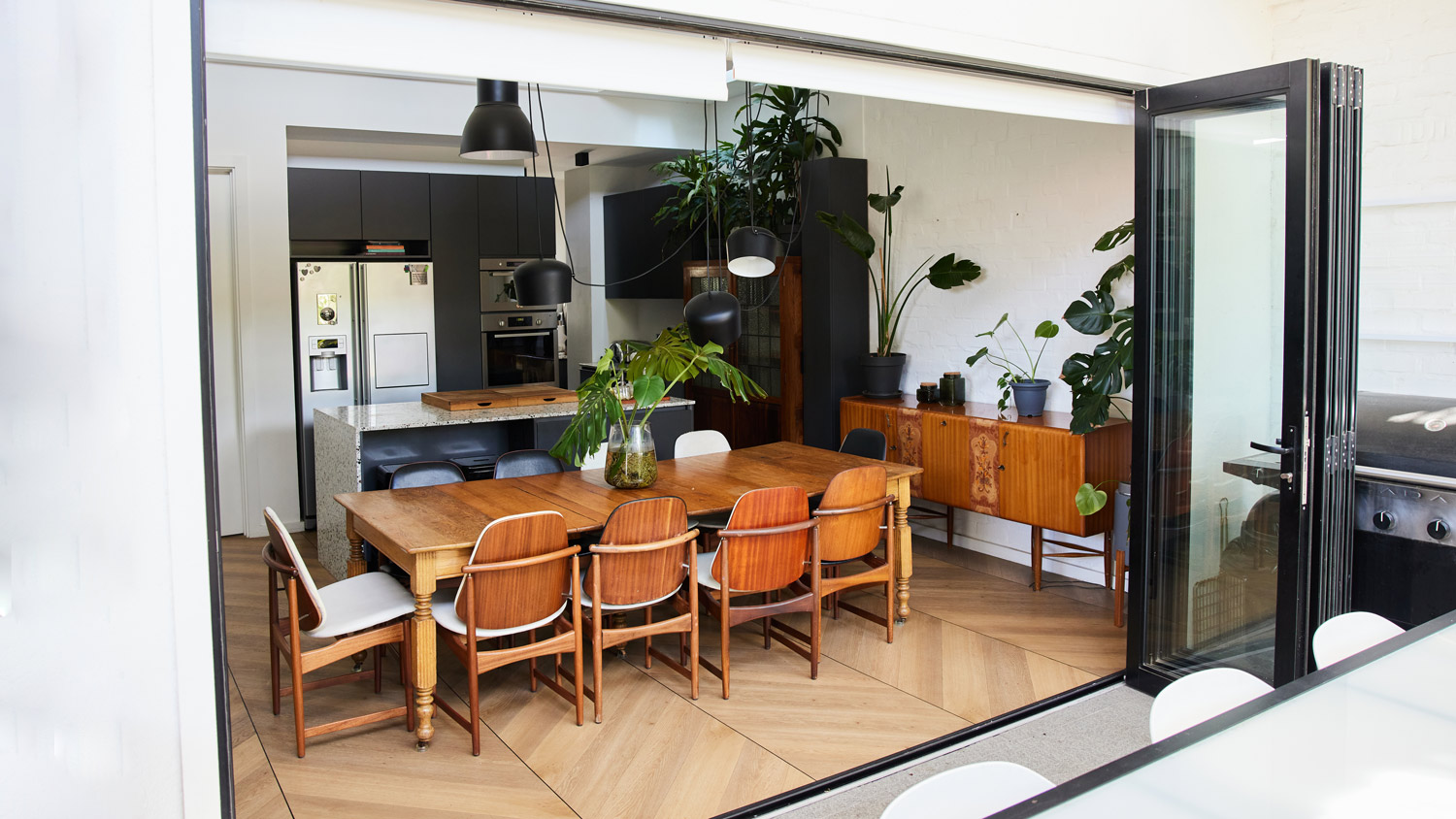 Dining area of modern home next to open doors leading to a patio