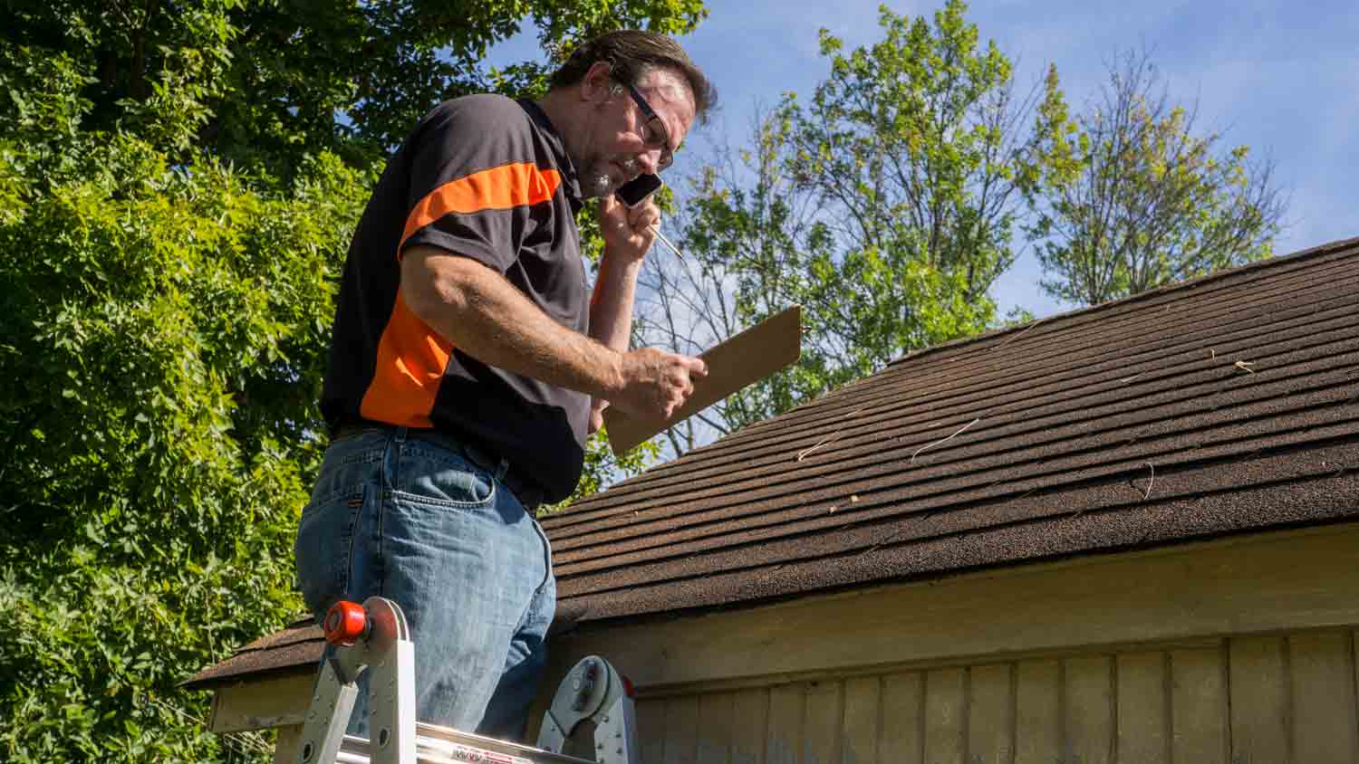 man inspecting hail damage on roof