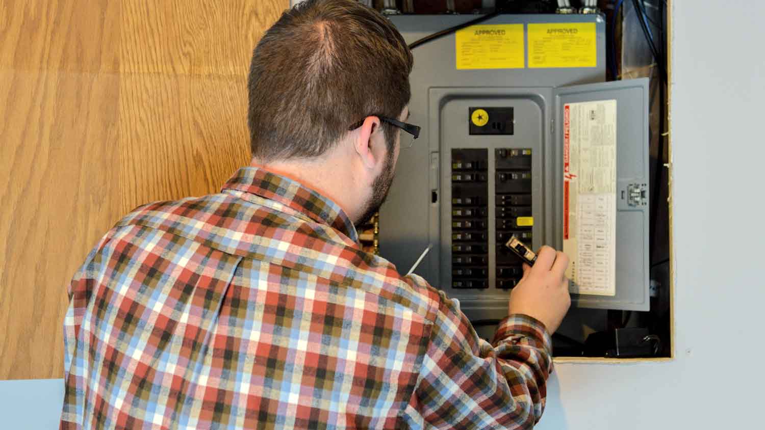 Handyman inspecting circuit breaker box at home