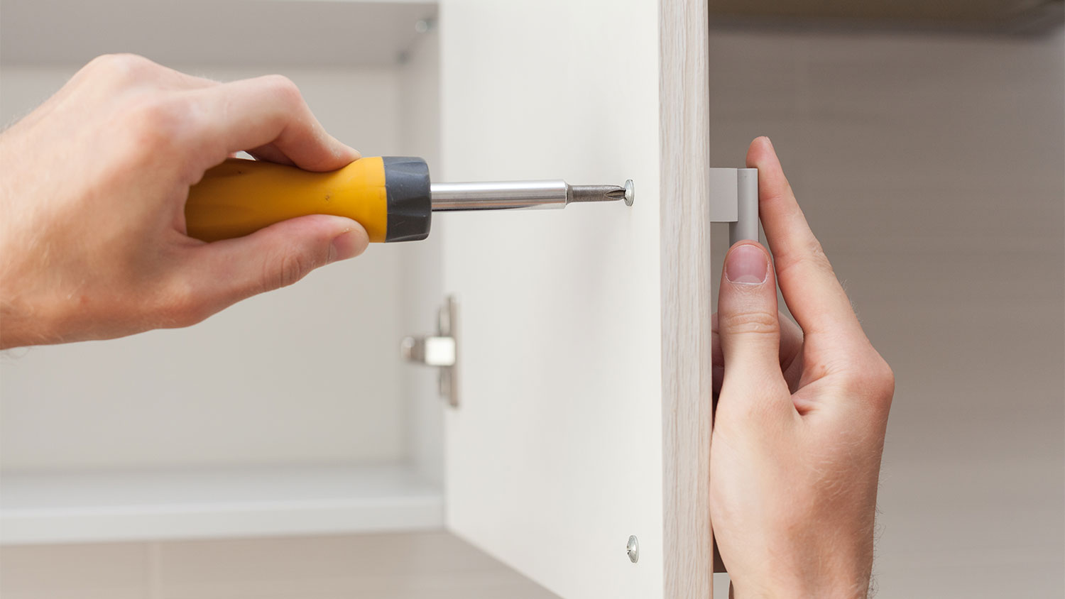 man installing handle on kitchen cabinet 