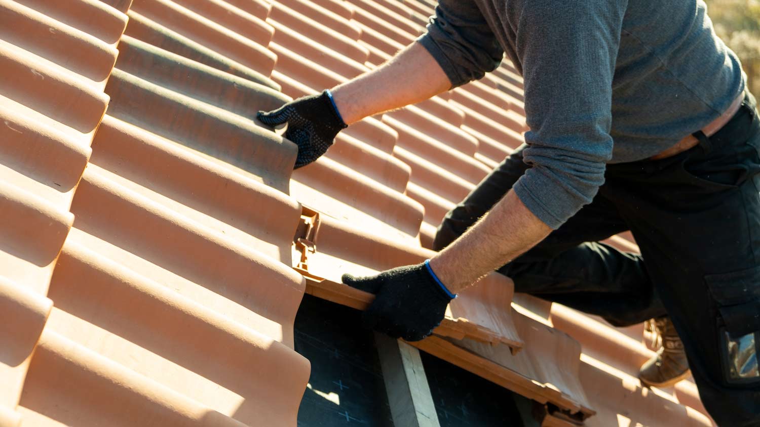 man installing new clay tiles  