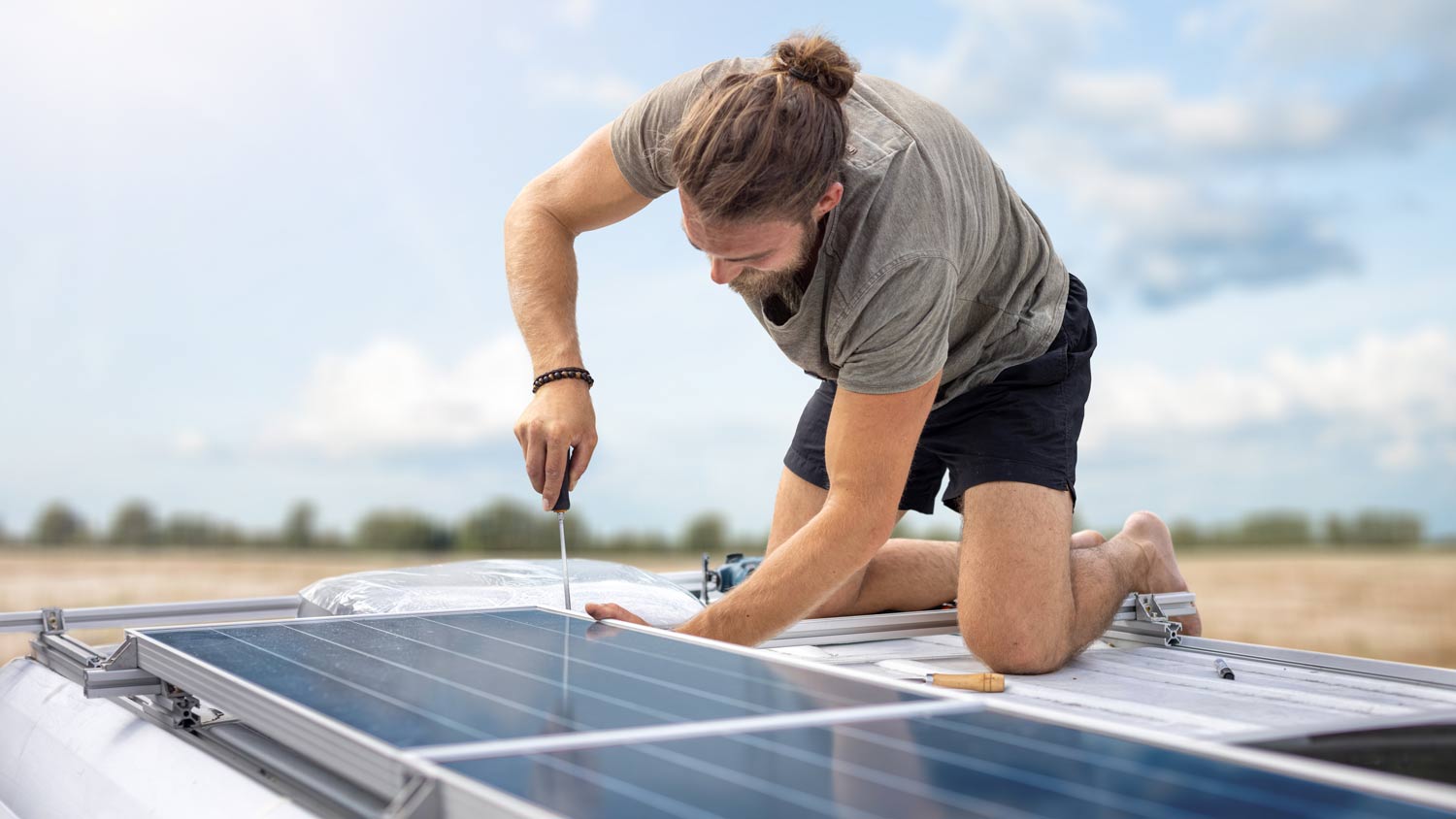 man installing solar panels on top of mobile home