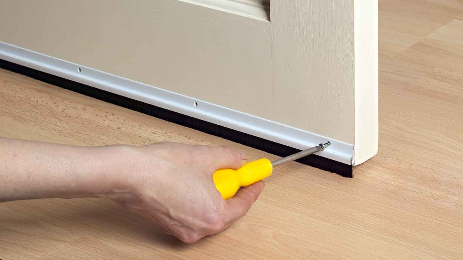 Worker installing rubber door sweep