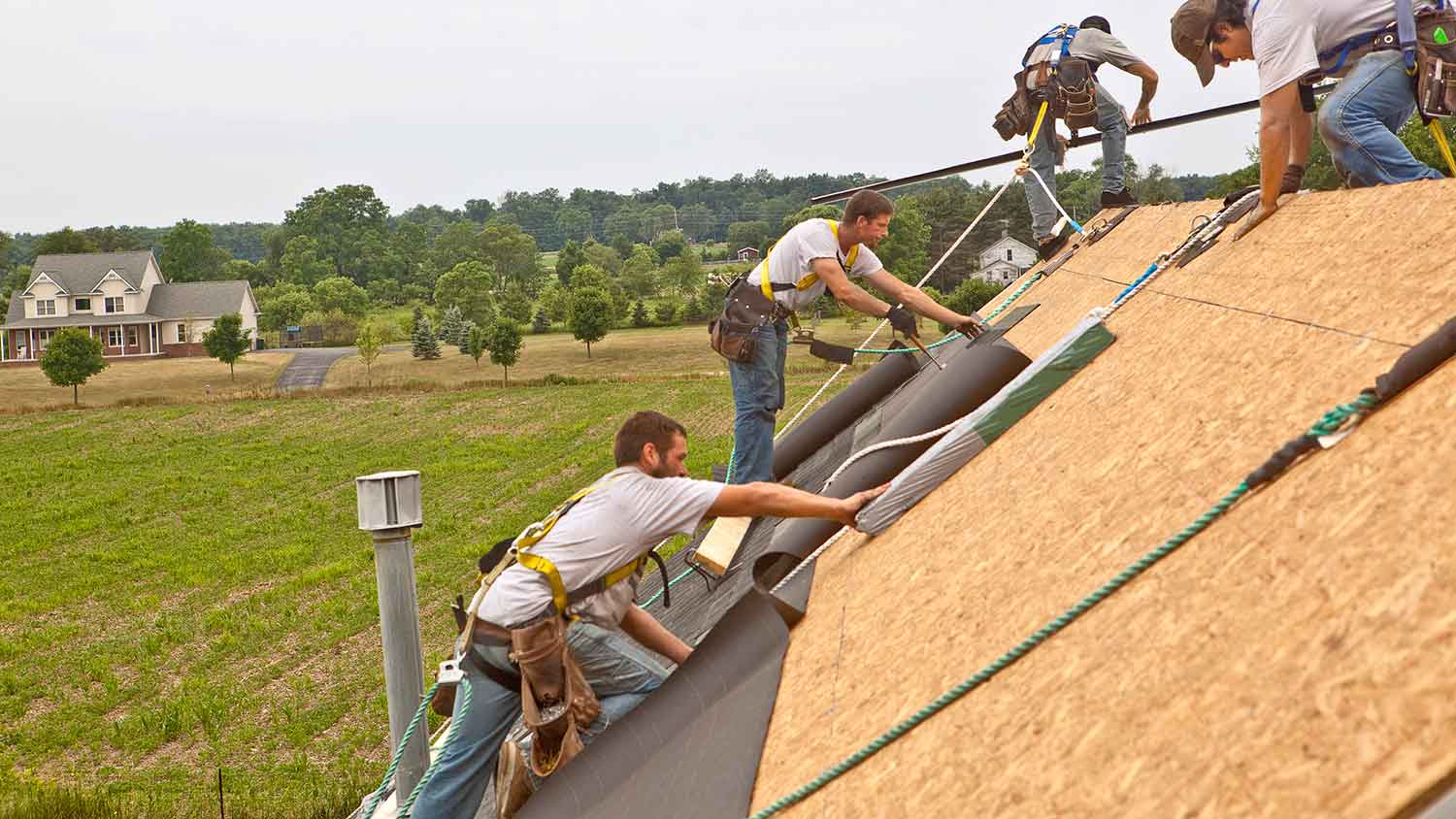 Roofers installing ice and water shield on the roof