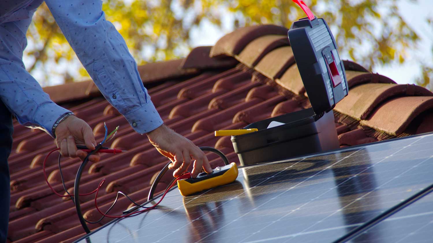 person installing solar panel on roof