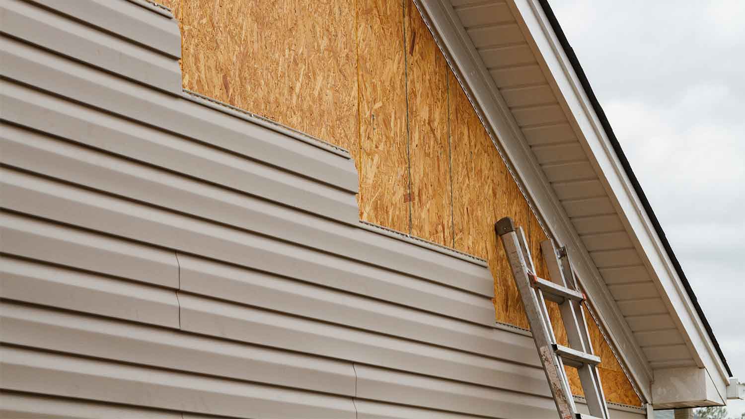 installing beige vinyl siding on home