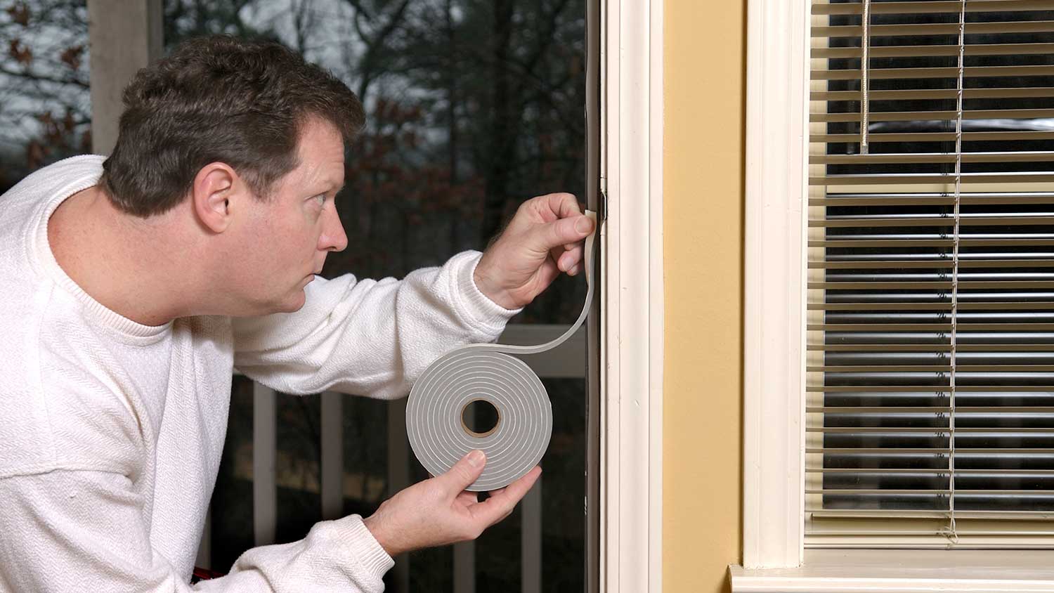 Handyperson installing weather stripping on a front door