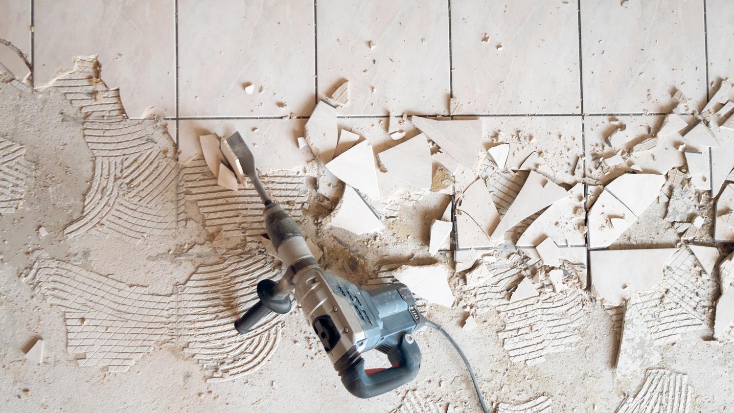 Top view of a jackhammer over broken tiles