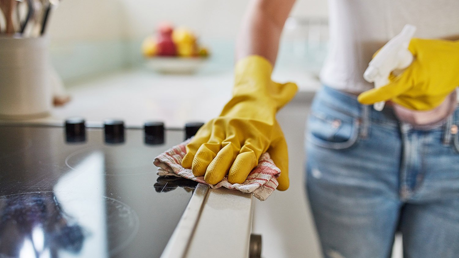 woman cleaning stovetop 	