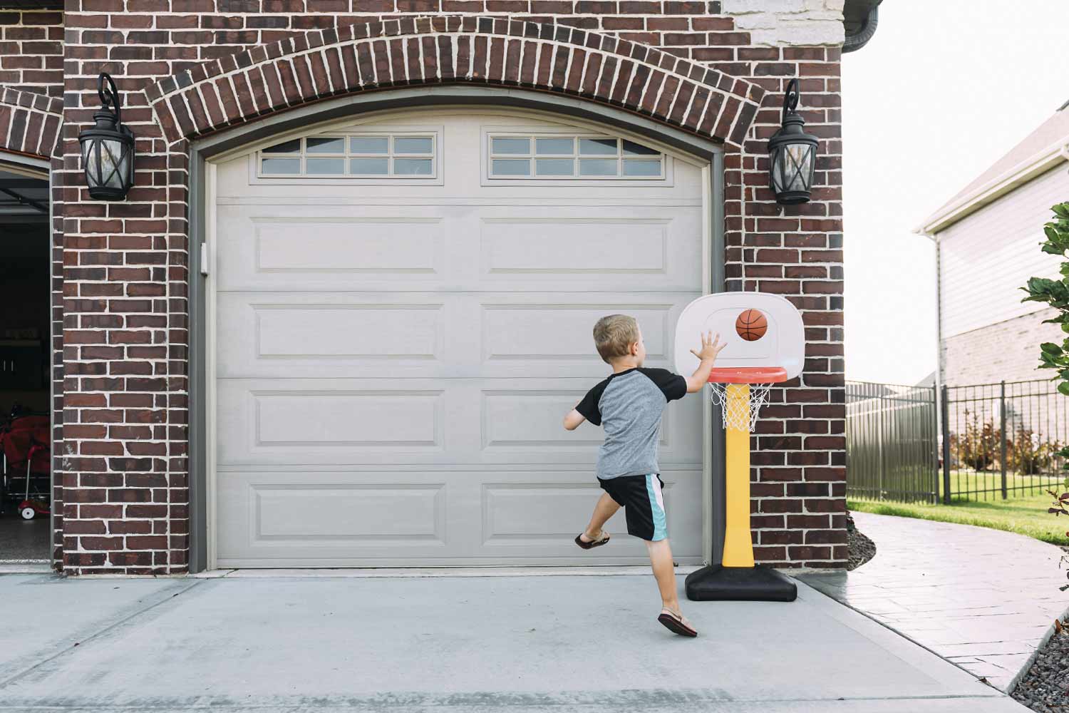 child playing with kid-size basketball hoop in driveway