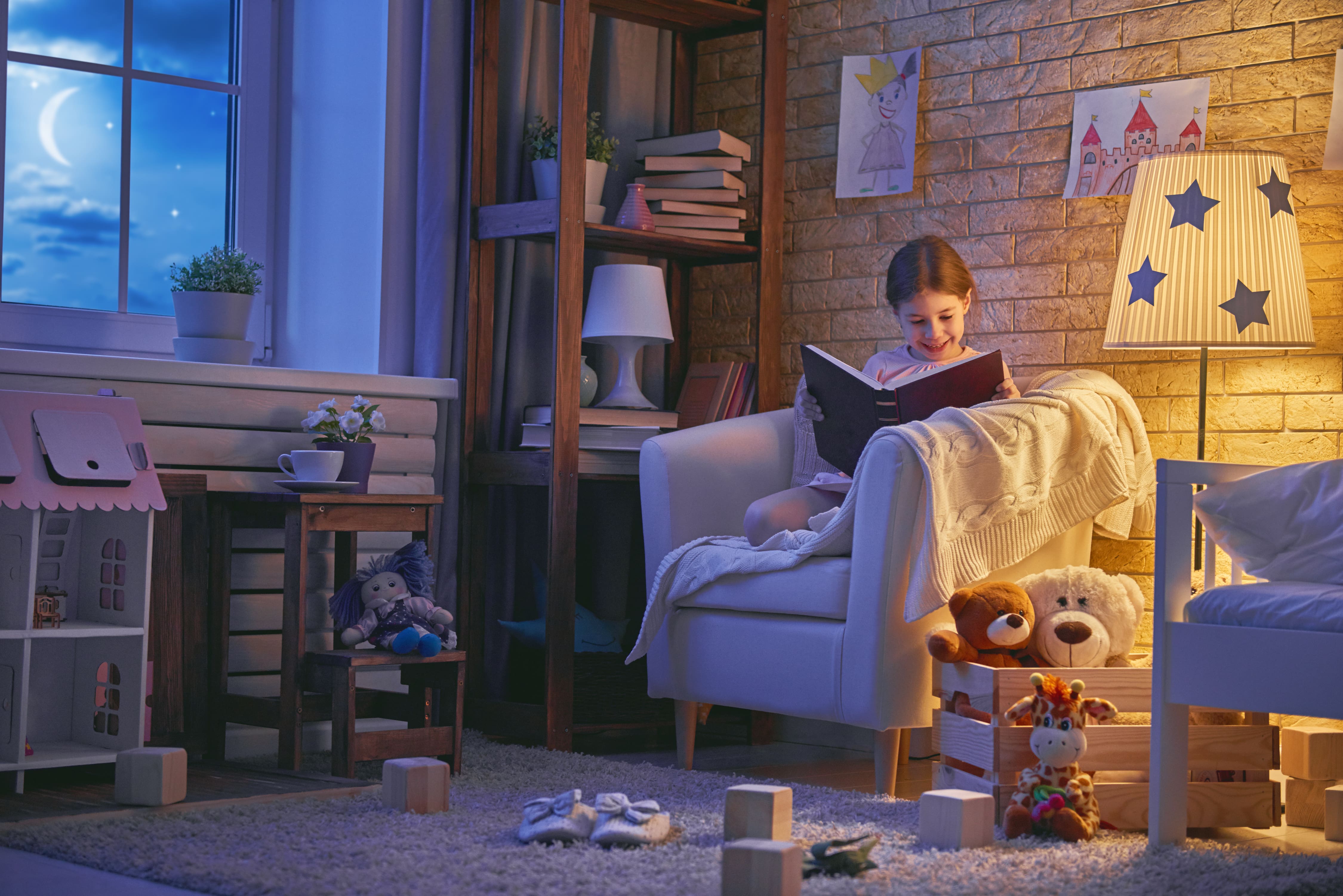 Little girl reading in book nook in room