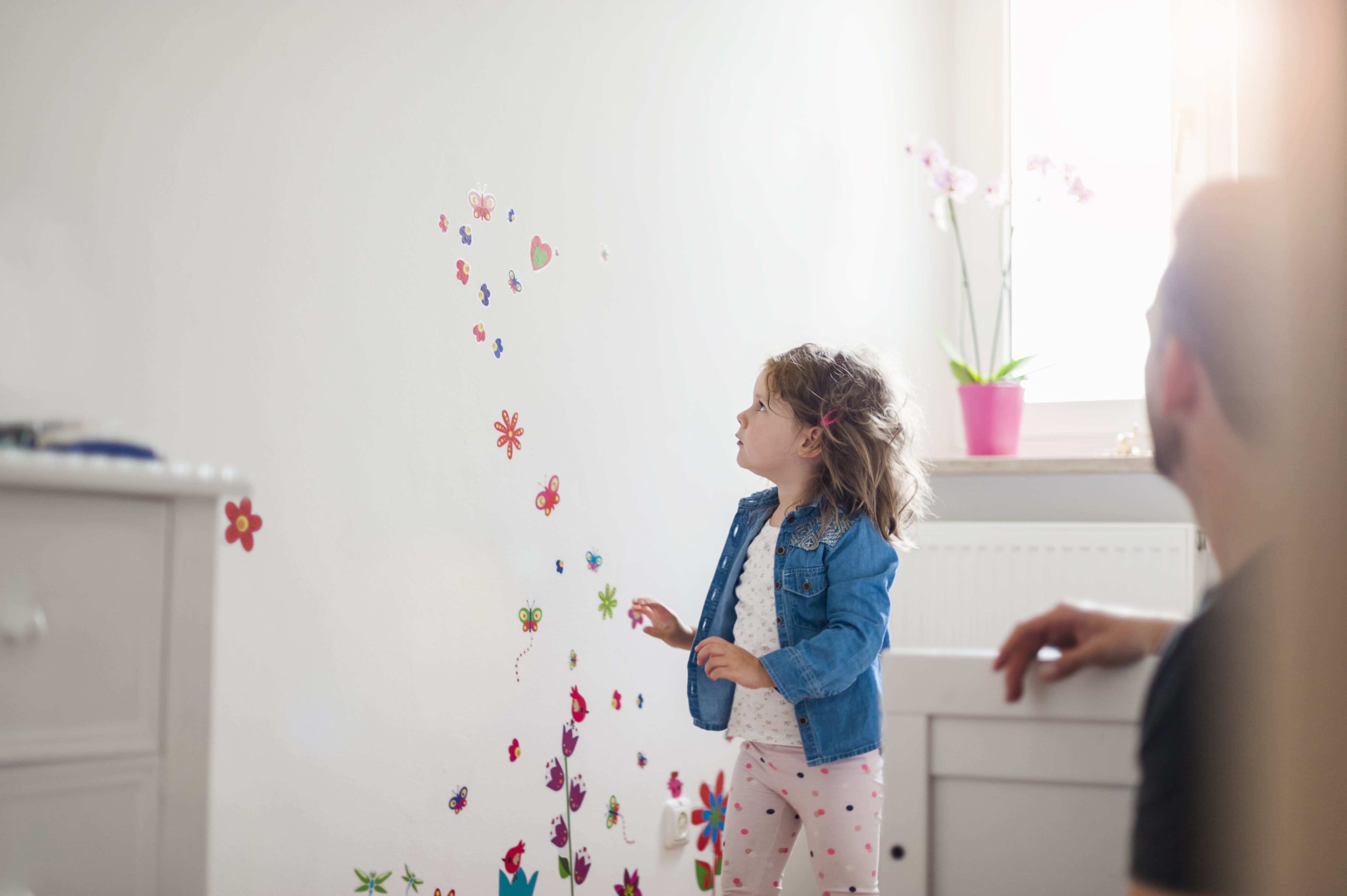 Girl applying peel-and-stick wall decals in her room 