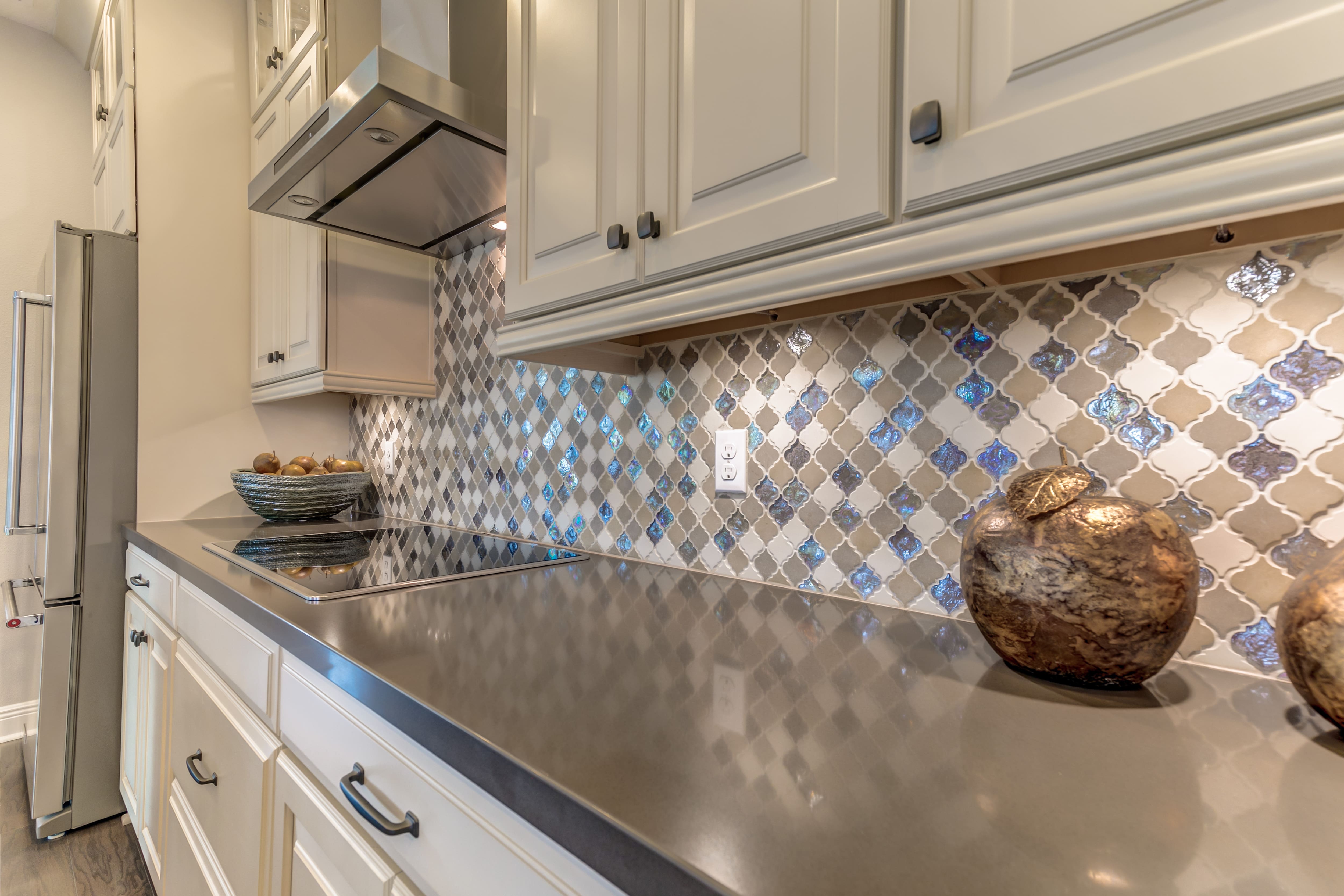 Gray kitchen cabinetry with a mosaic backsplash with mixed materials 