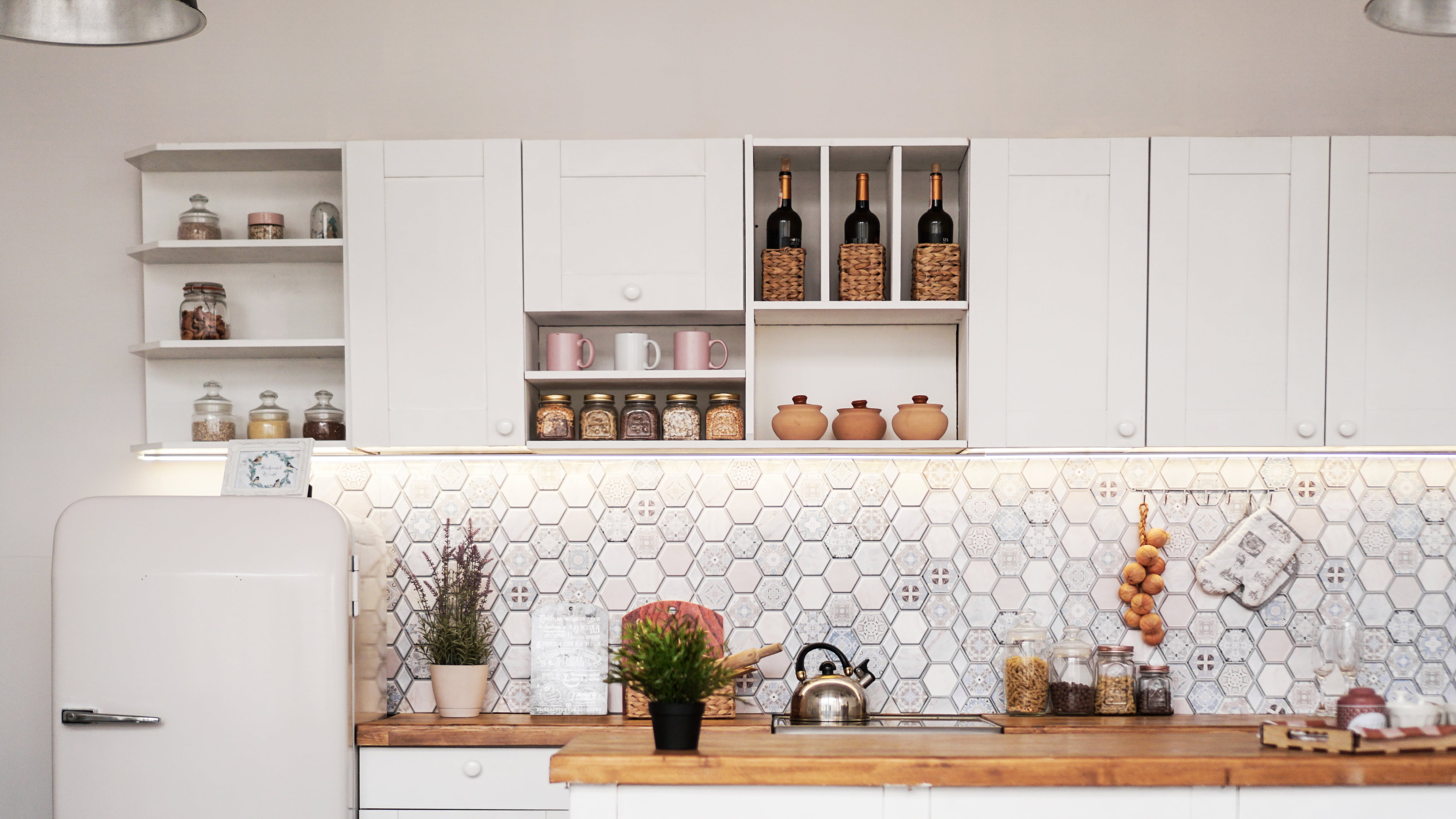 A modern white kitchen with a purple patterned hexagon backsplash