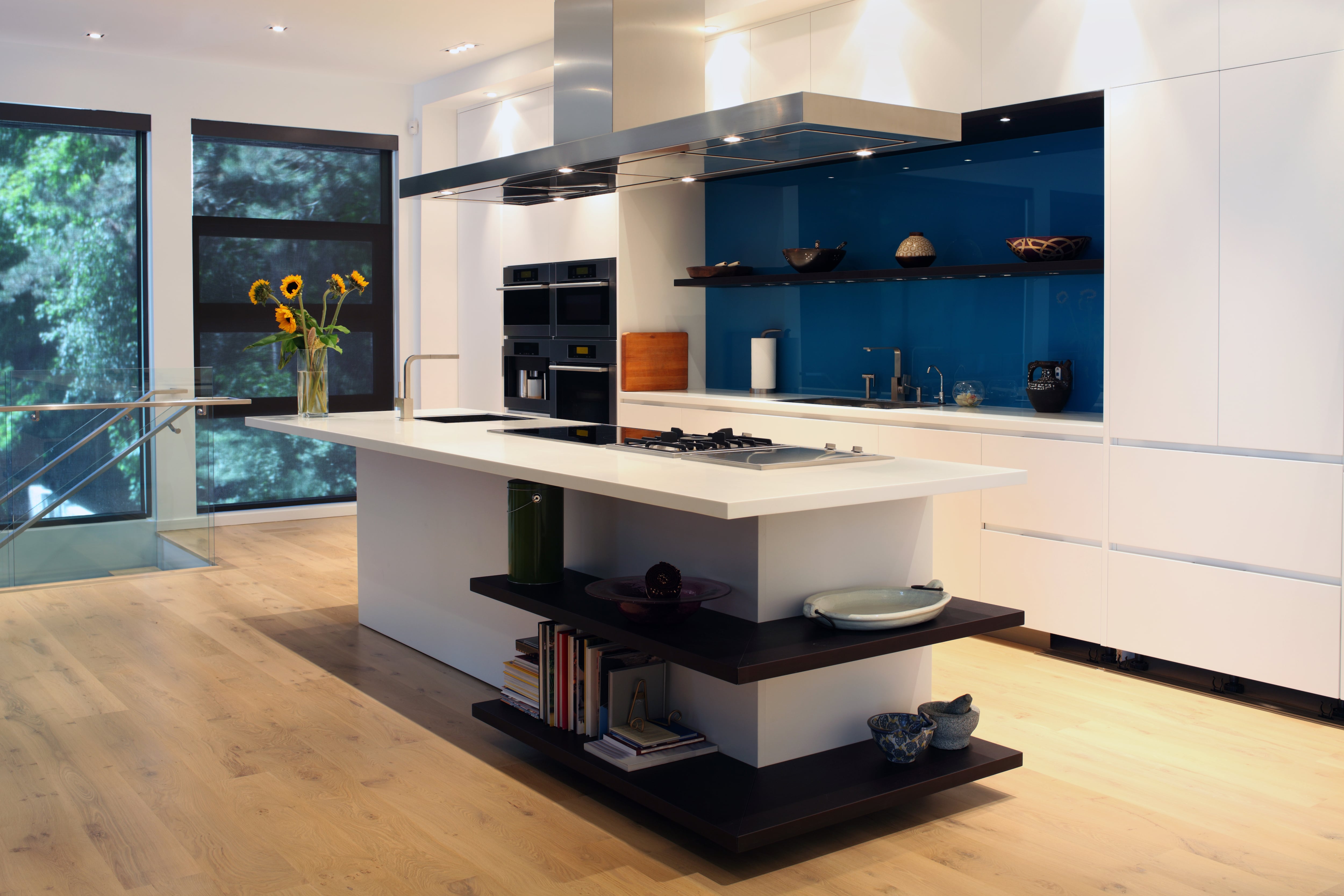 A white kitchen with a dark blue glass backsplash 