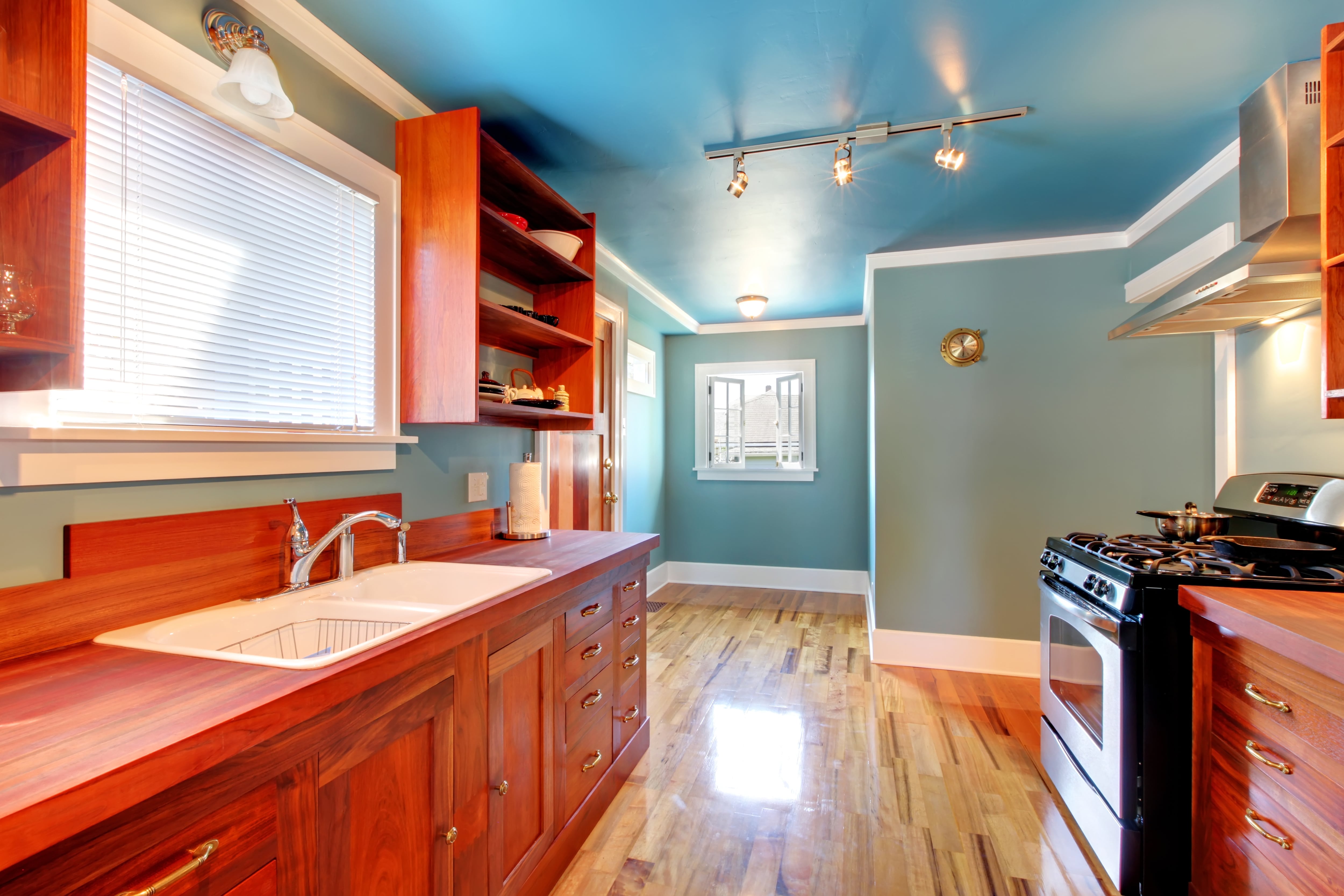 A kitchen with brightly stained wooden cabinetry and light blue walls