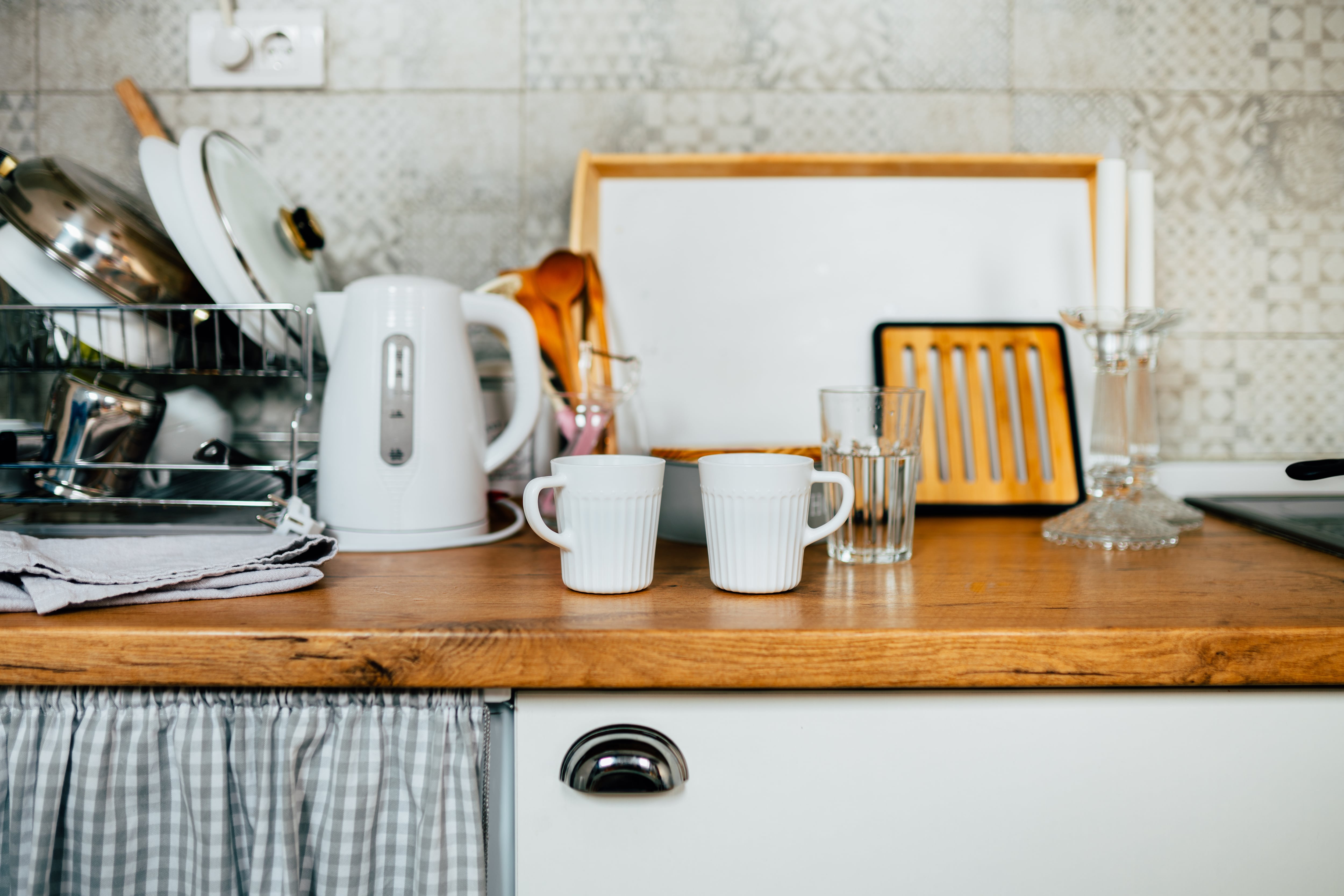 Small kitchen with white cabinets and butcher block countertop with assorted dishware on top