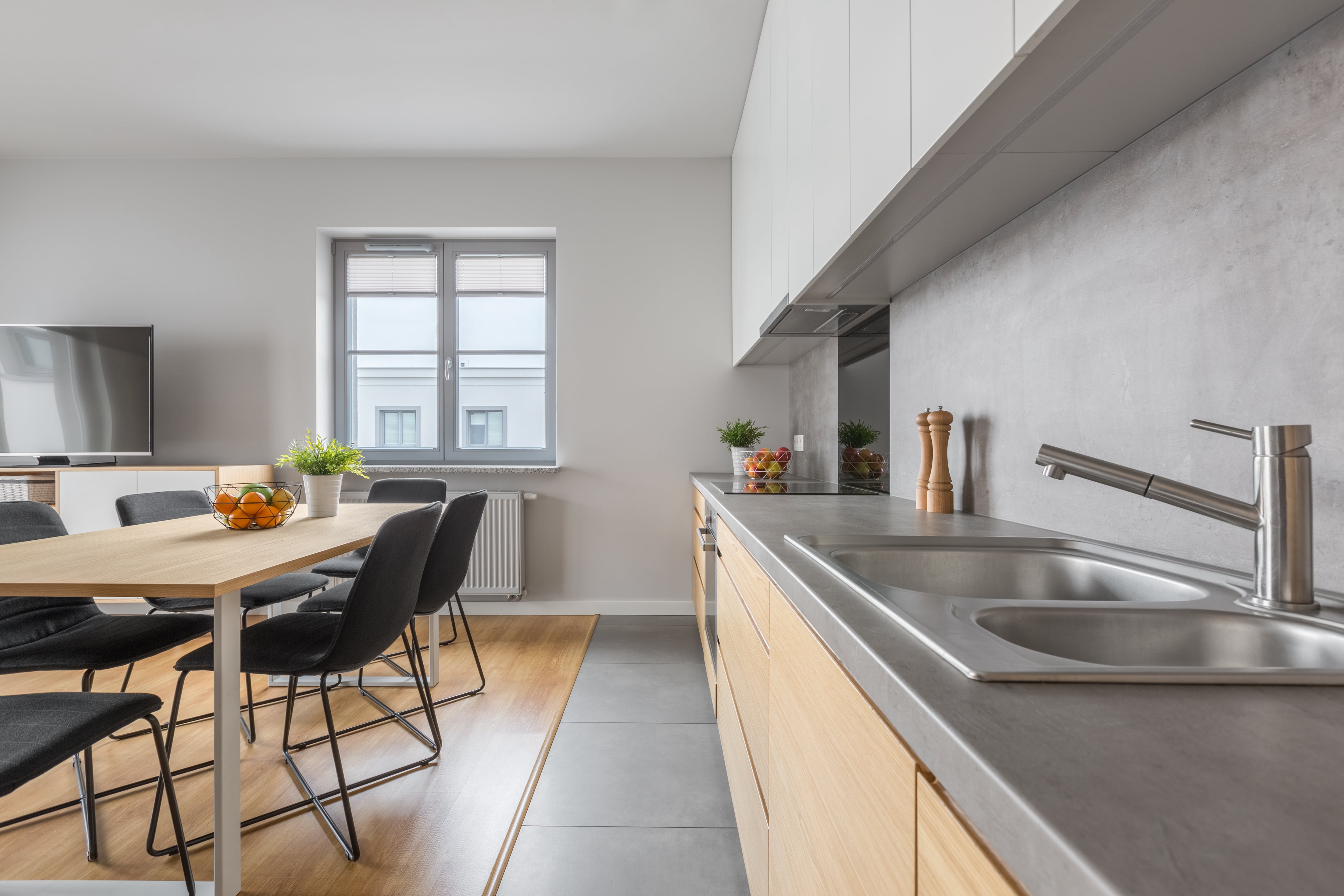 Modern gray one-wall kitchen with concrete countertops across from wood kitchen table