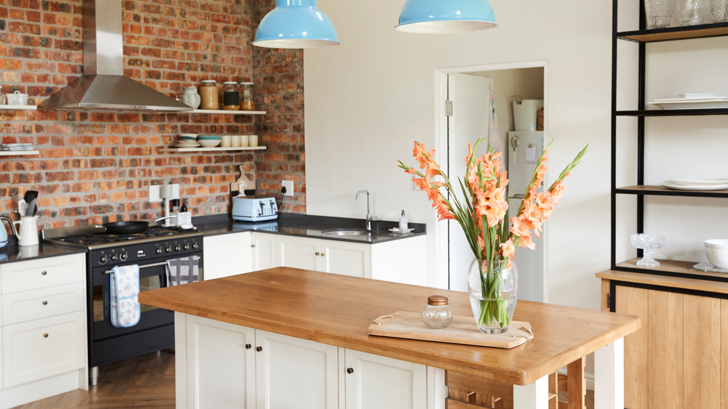 The interior of an open kitchen plan with exposed brisk as backsplash