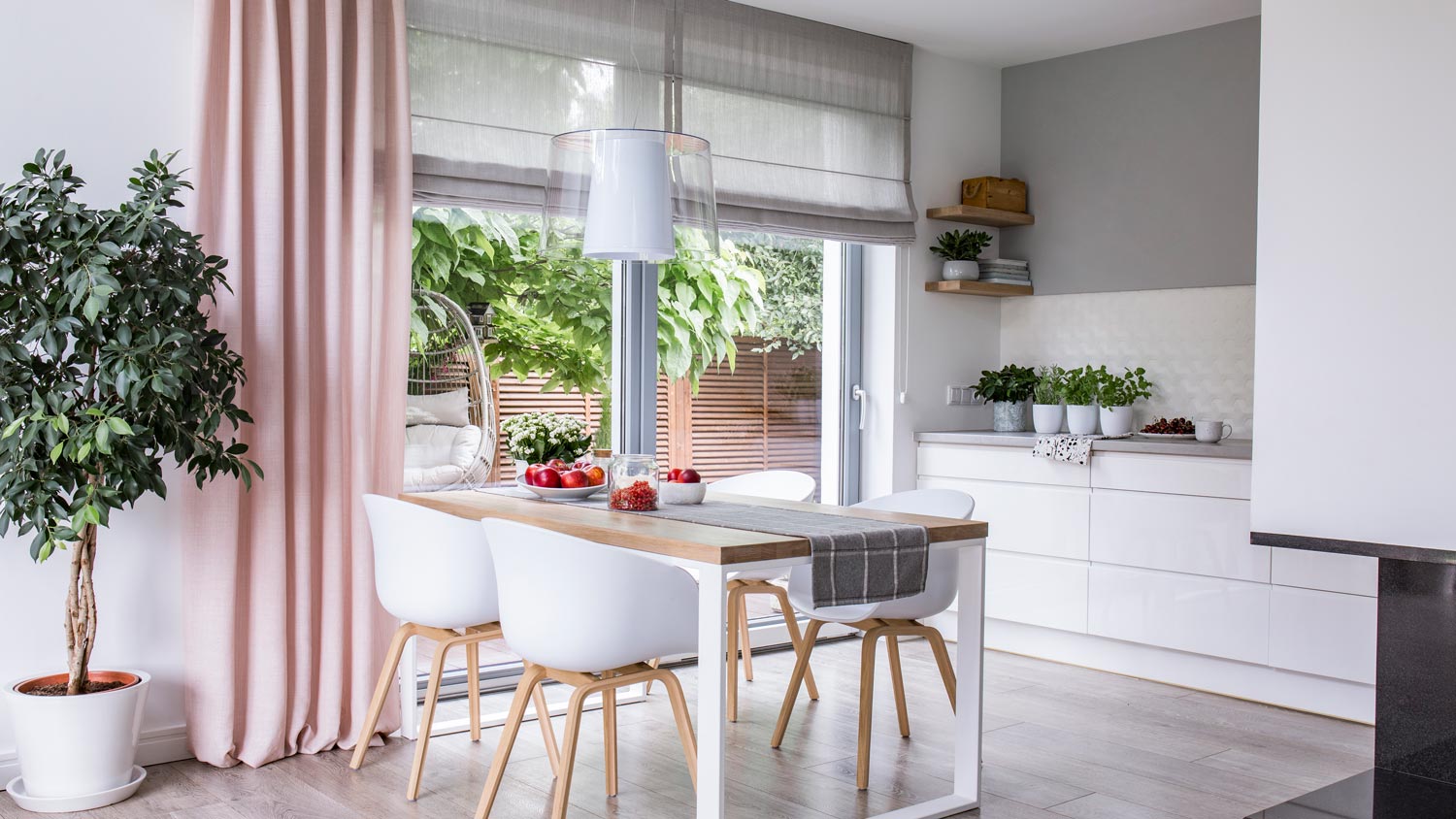 The interior of a kitchen with grey roman shades