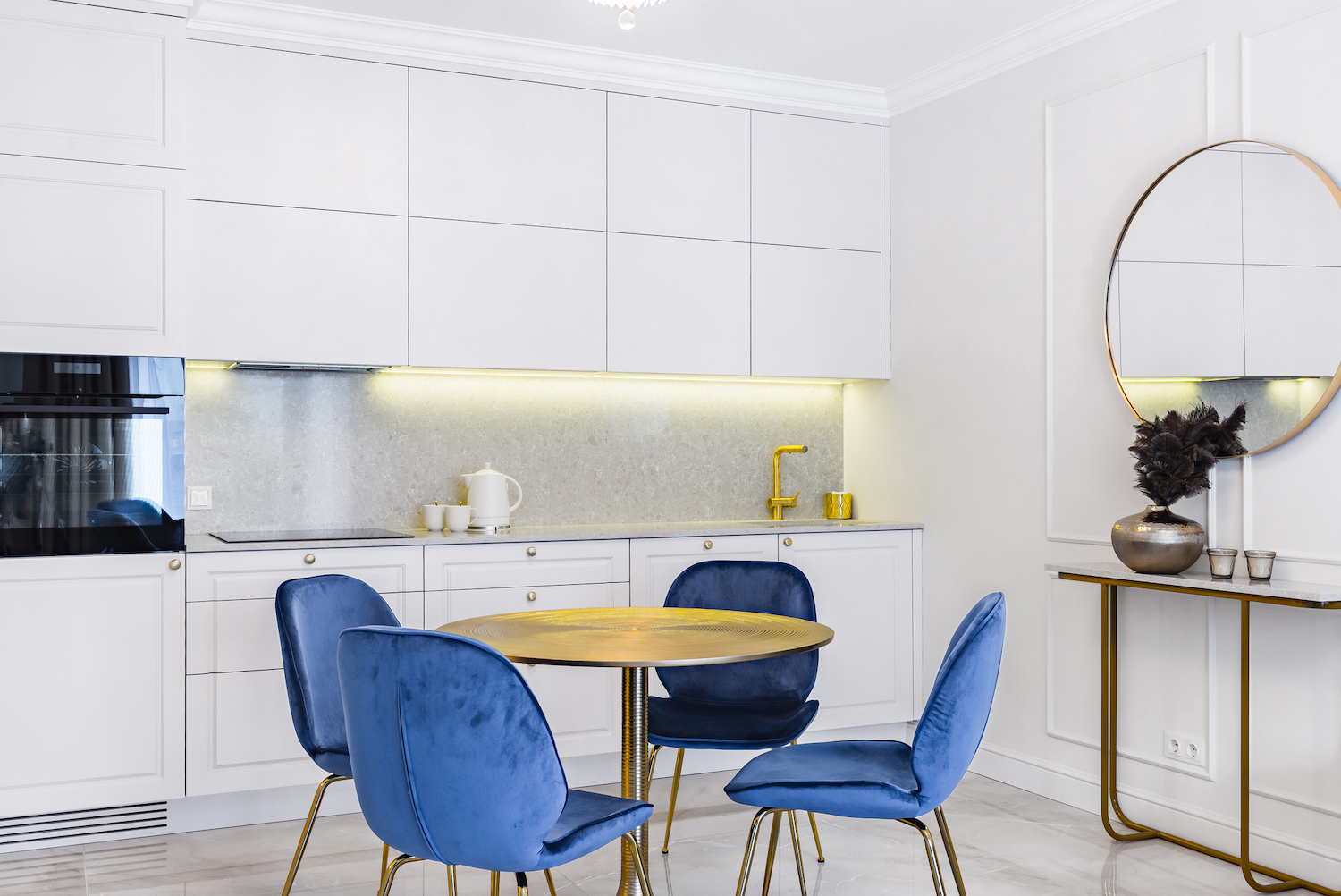 A modern kitchen with an led light rope shining underneath the white cabinets