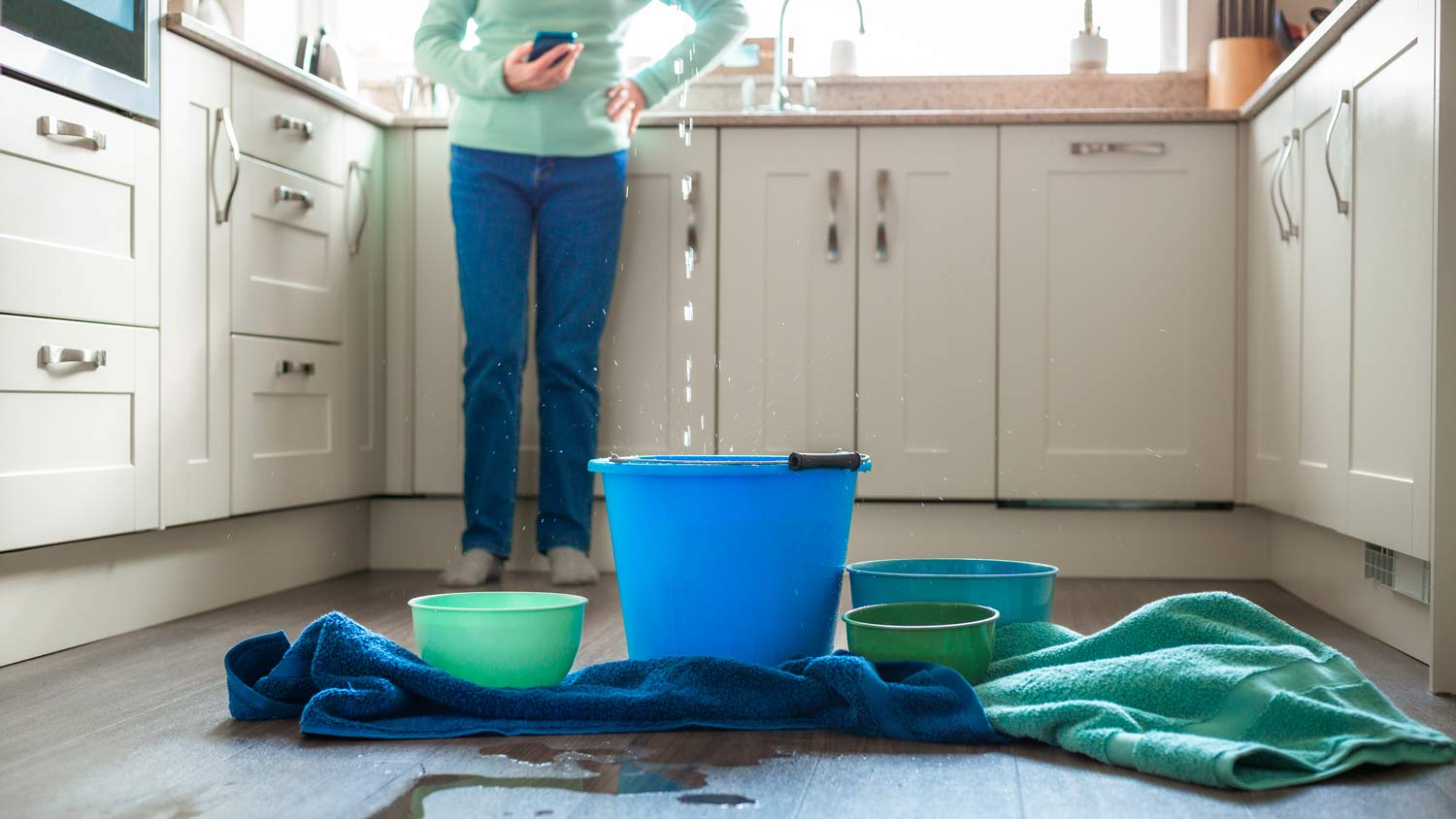 woman surrounded by water leak in kitchen